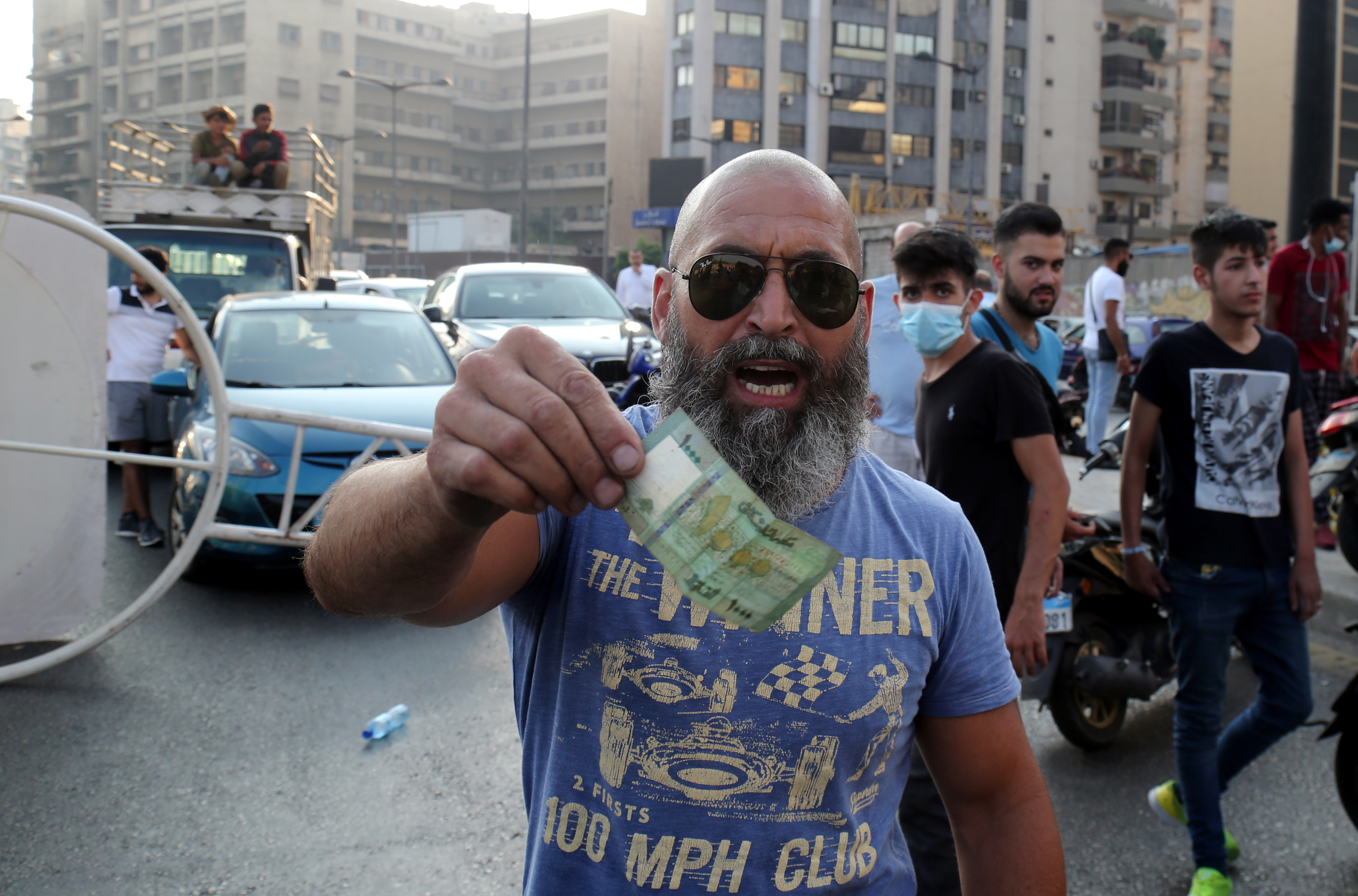 A man gestures with a currency note as Lebanese protesters block the roads with garbage bins and burning tires during protests after Lebanese Prime Minister-Designate Saad Hariri abandoned his effort to form a new government, in Beirut, Lebanon, 15 July 2021.
