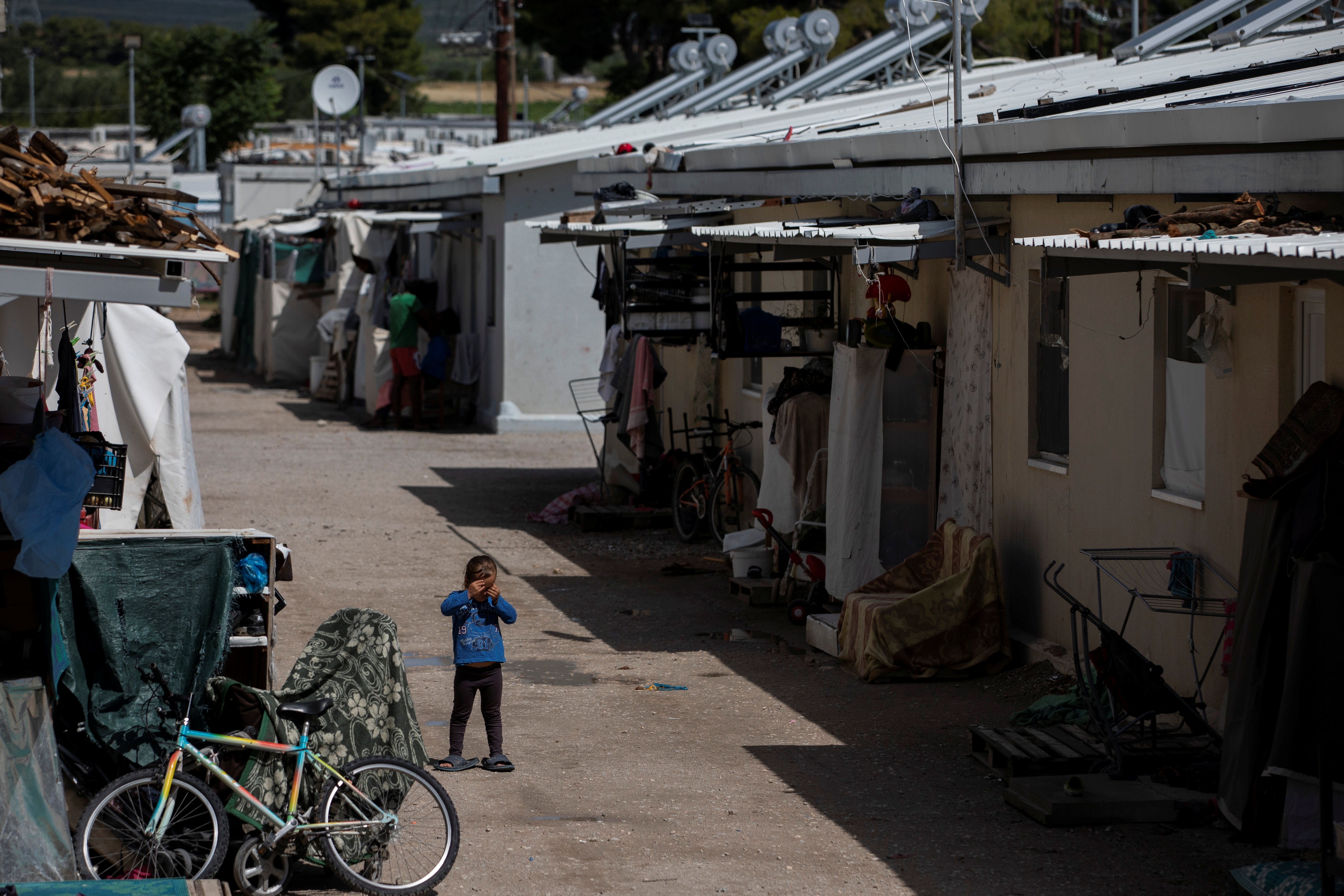 A child stands next to shelters inside the Ritsona camp for refugees and migrants, in Greece, June 15, 2021 [Alkis Konstantinidis/Reuters]