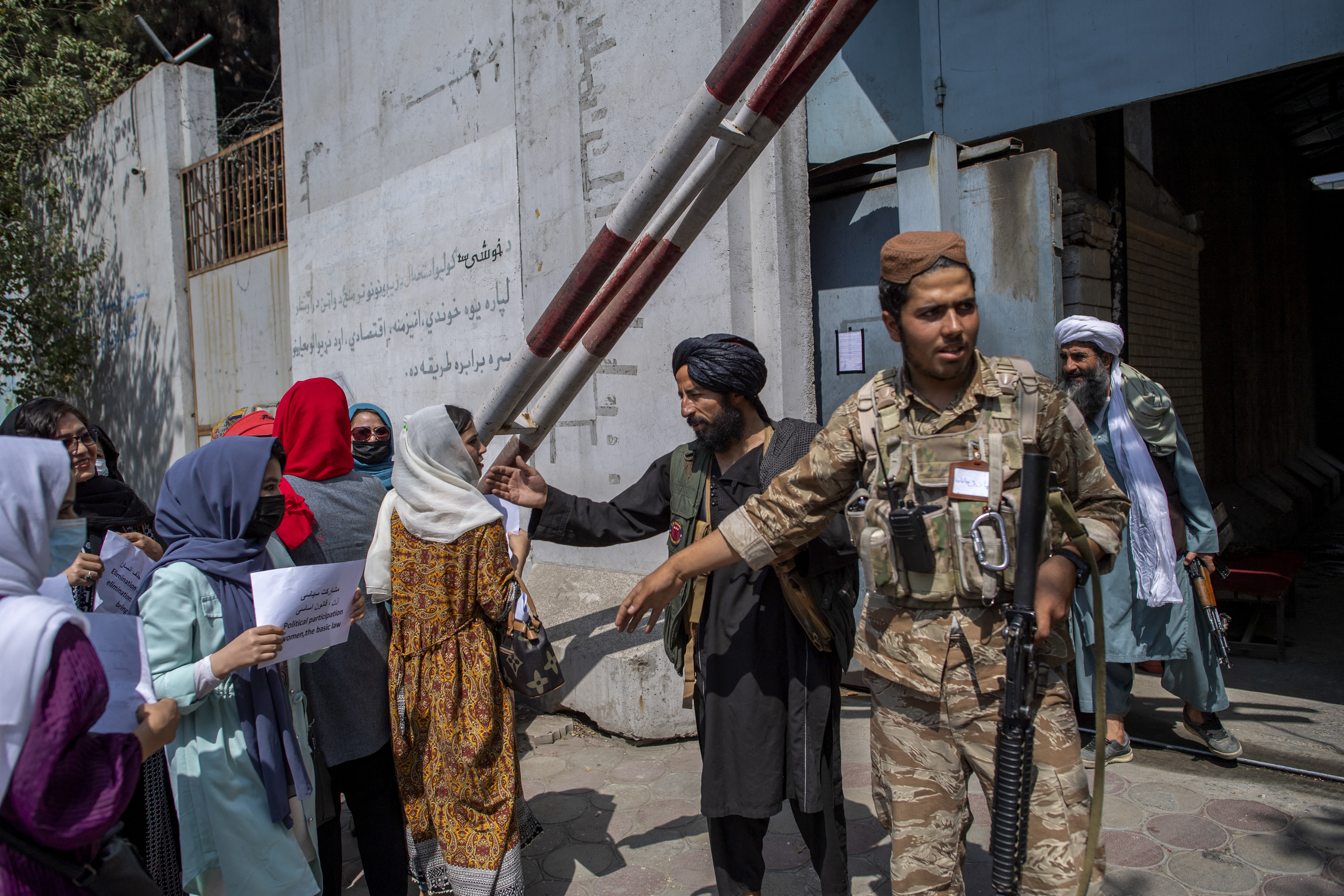 Afghan women converse with a Taliban fighter while they hold placards during a demonstration demanding better rights for women in front of the former Ministry of Women Affairs in Kabul on September 19, 2021