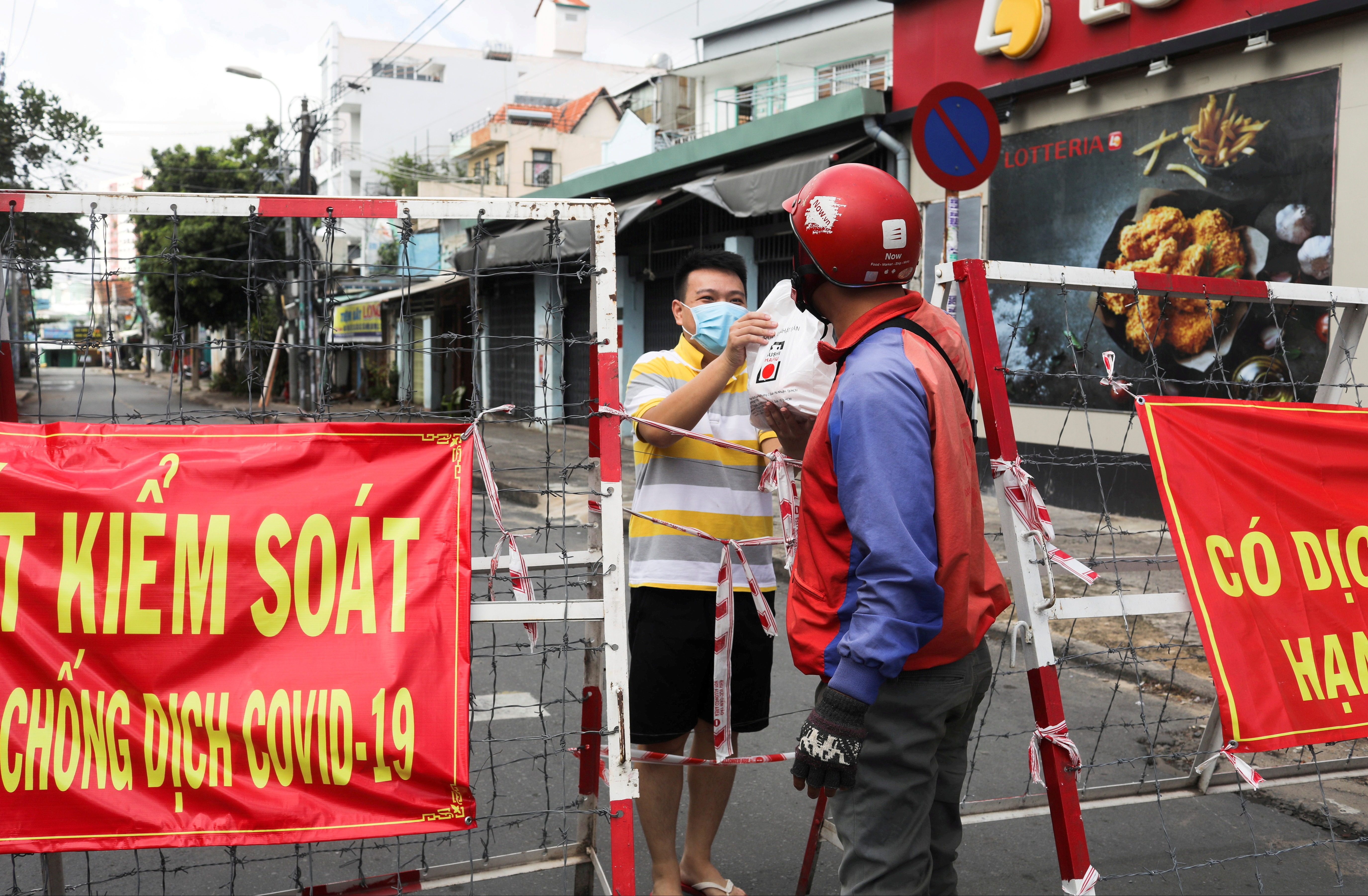 A man living in an area under lockdown receives food through a barricade during the COVID-19 pandemic in Ho Chi Minh City, Vietnam July 20, 2021 [File: Reuters]
