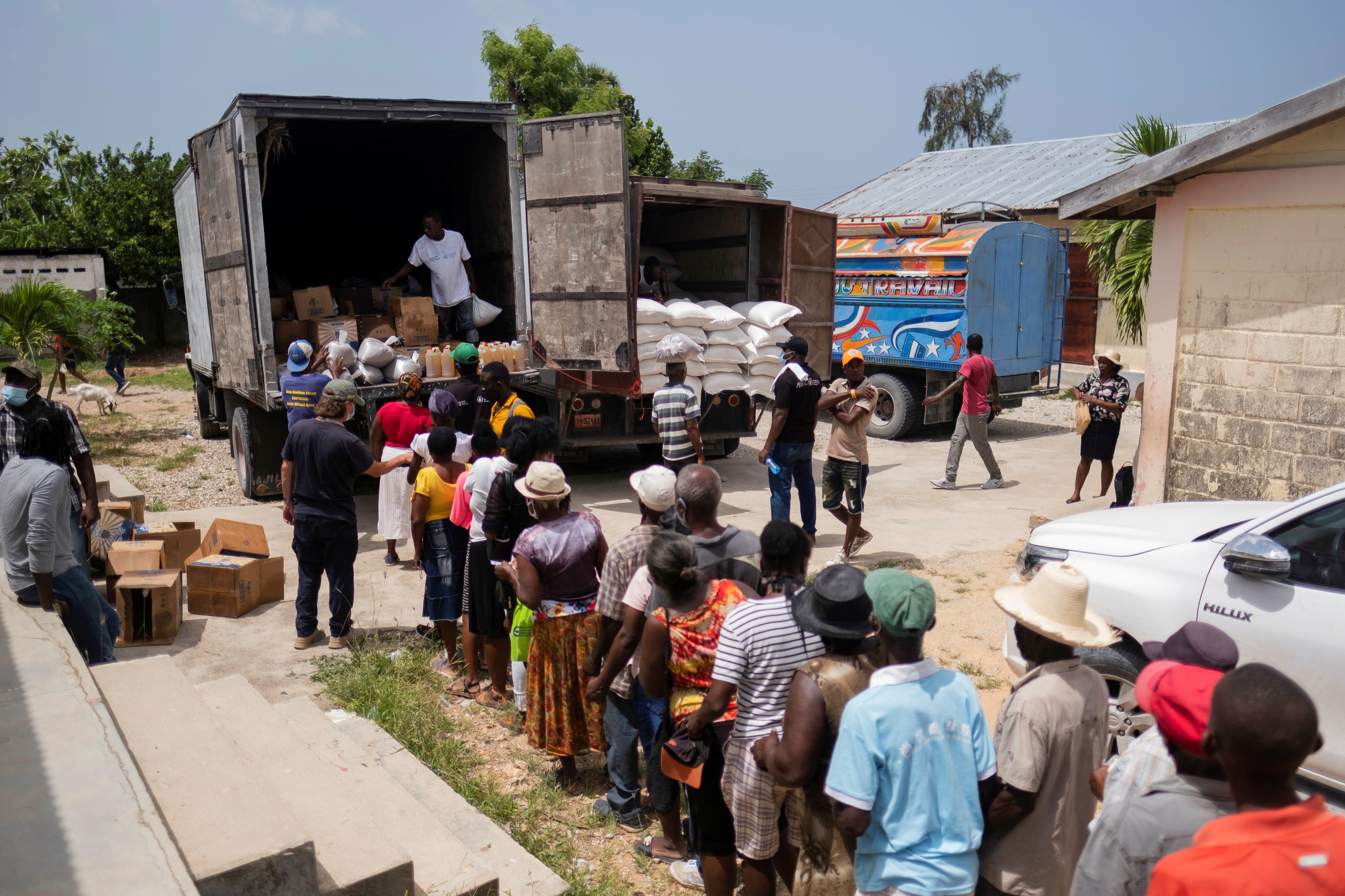 People affected by the August 14 earthquake wait for food provided by the World Food Program, at a school in Port Salut, Haiti on August 24, 2021 [Reuters/Ricardo Arduengo]