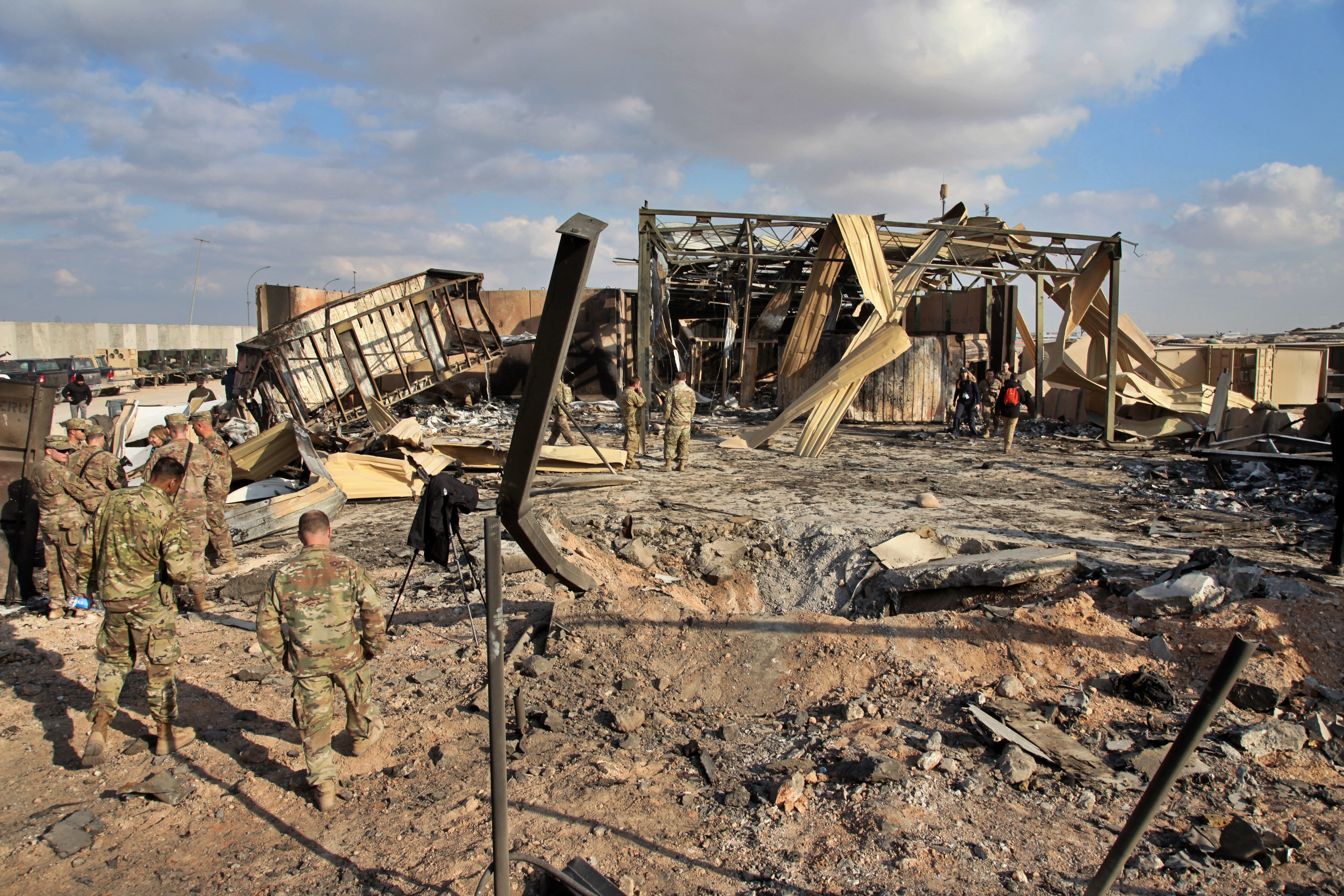 US soldiers stand at the spot hit by Iranian bombing of Ain al-Asad airbase, in Anbar, Iraq [File: Qassim Abdul-Zahra/The Associated Press]