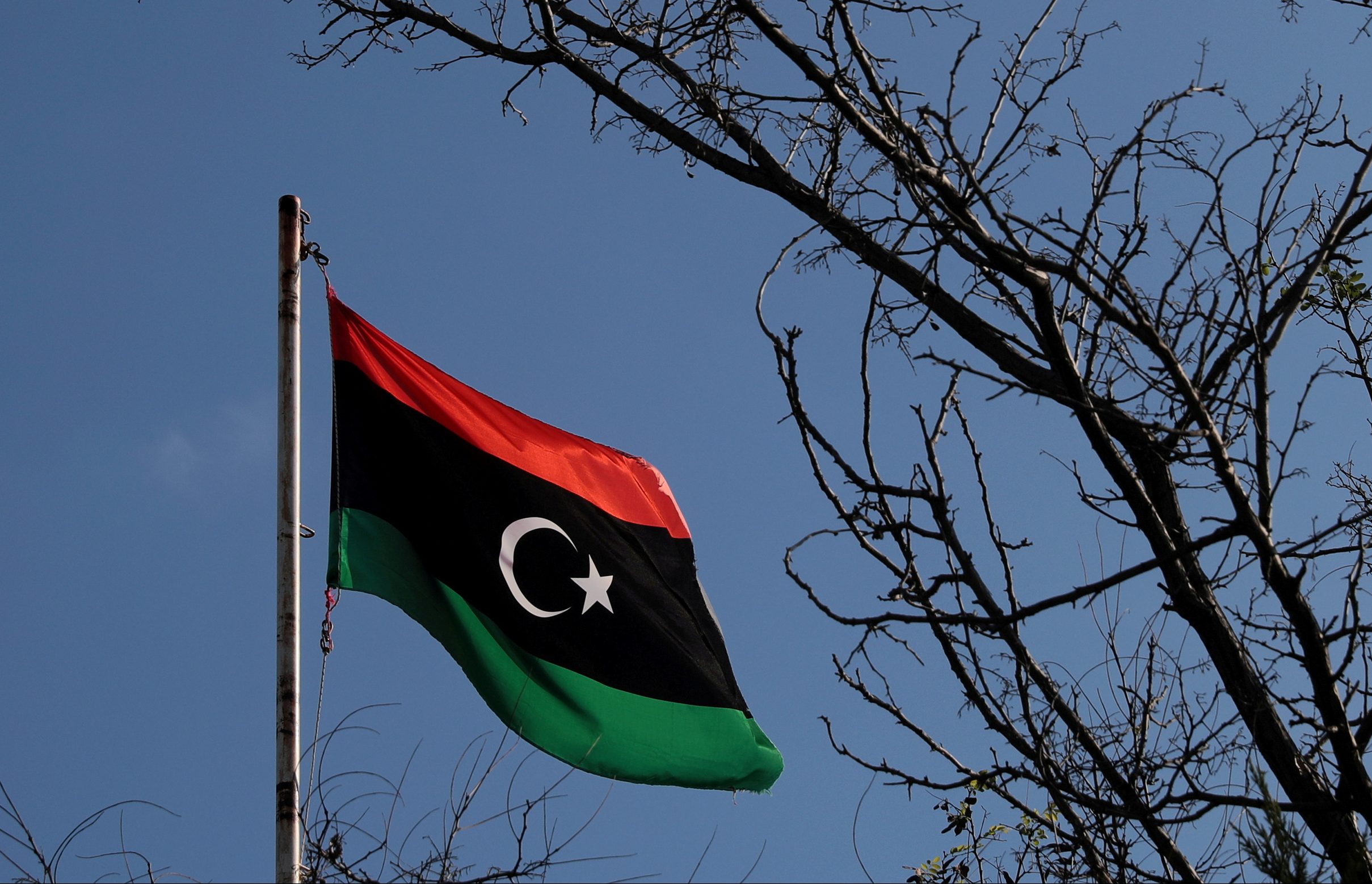 A Libyan flag flutters in the air.