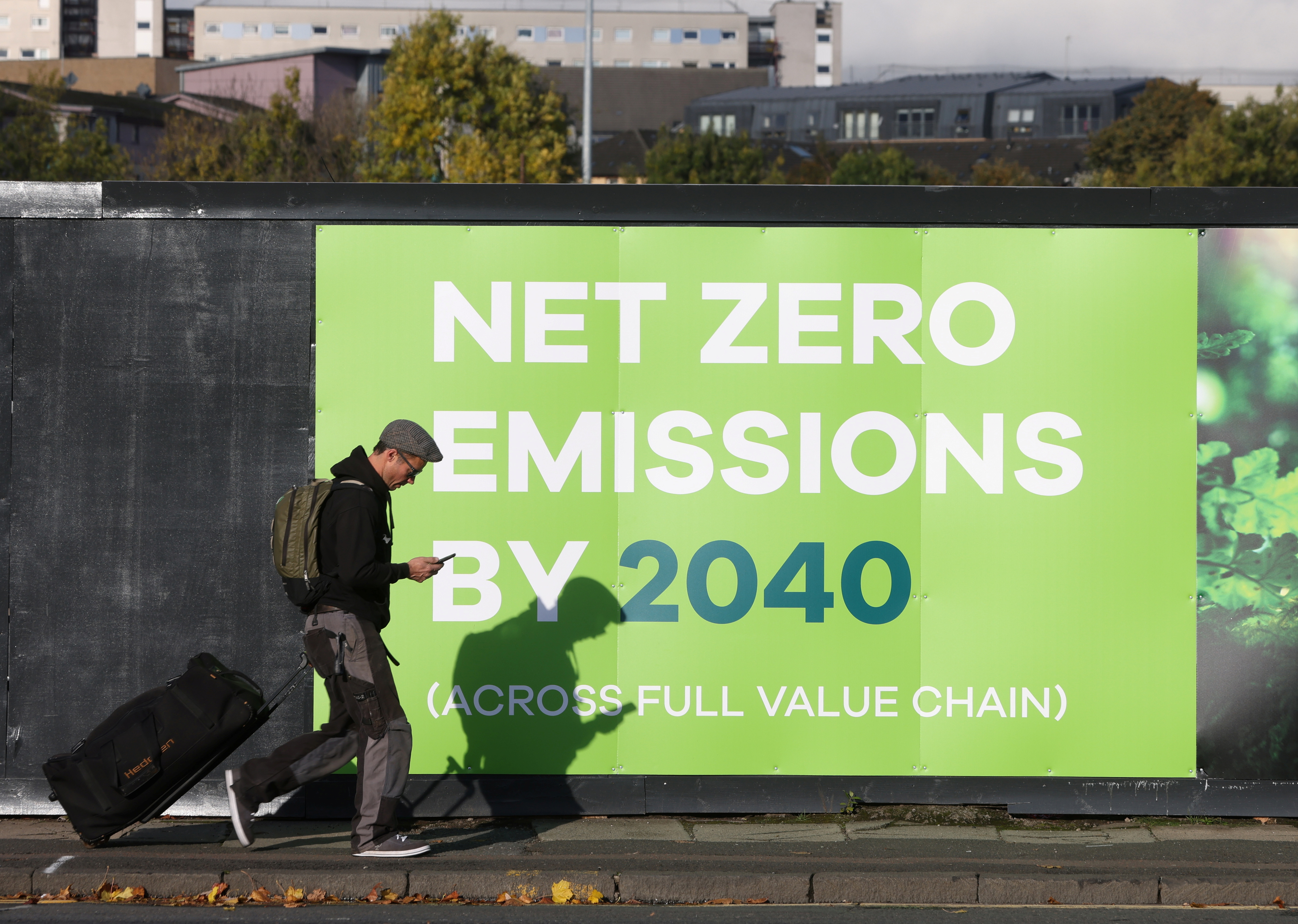A man walks past an advertisement near the venue for the UN Climate Change Conference (COP 26) in Glasgow, Scotland on October 30, 2021 [Reuters/Yves Herman]