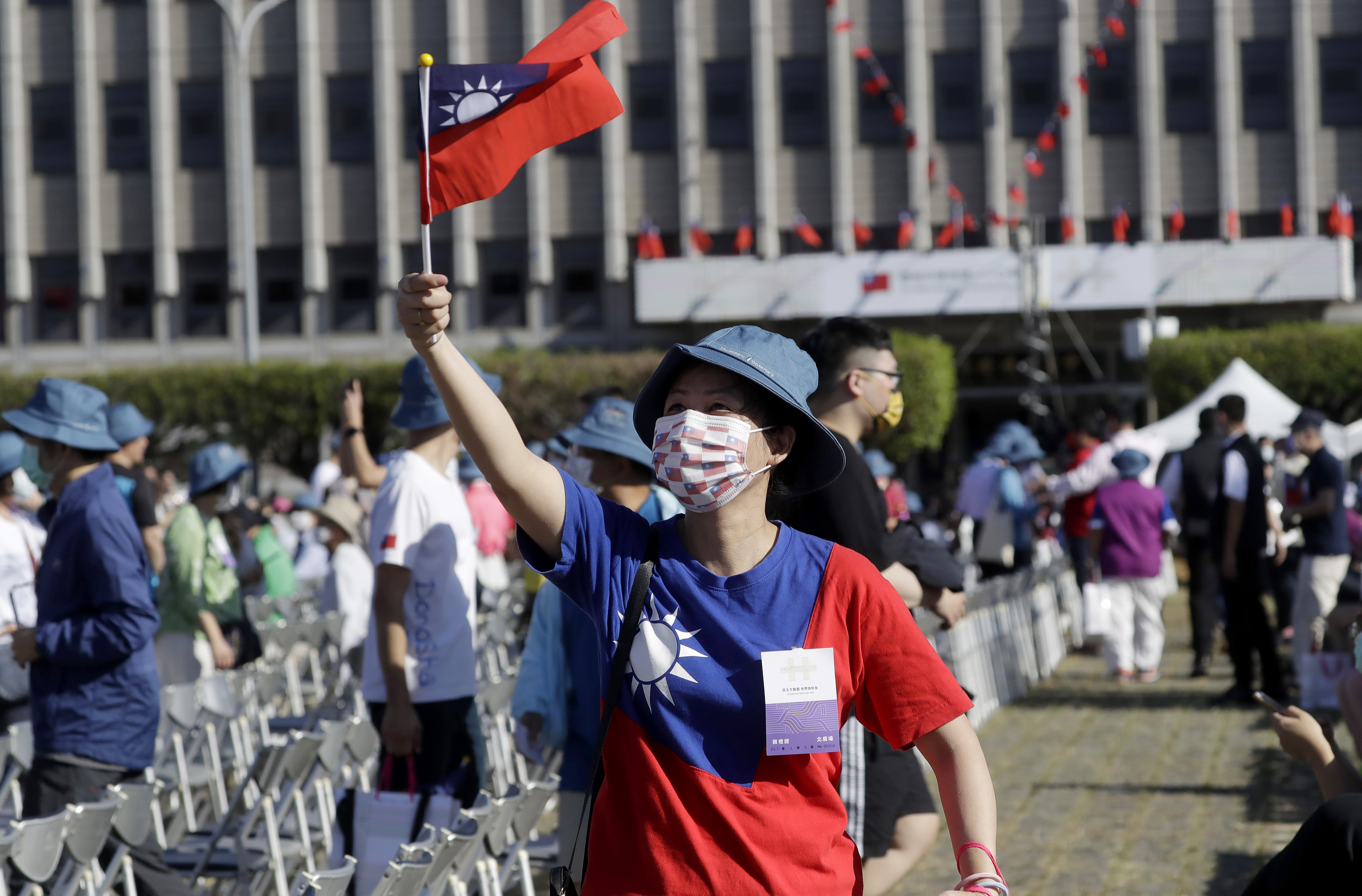 A woman holds and wears Taiwan’s national flag during National Day celebrations in front of the Presidential Building in Taipei, Taiwan, on Sunday, October 10, 2021