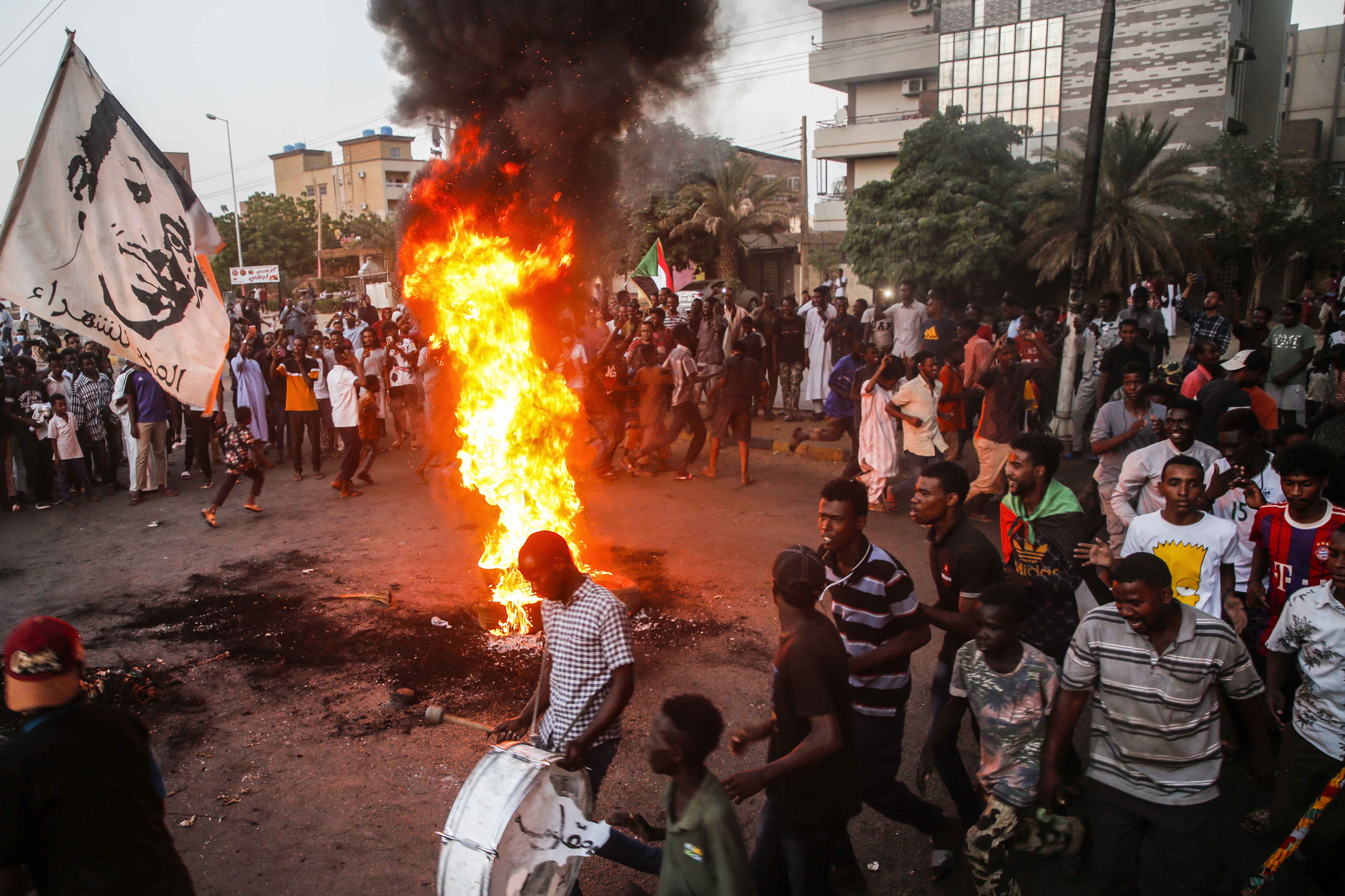 Sudanese protesters chant slogans next to burning tires during a demonstration