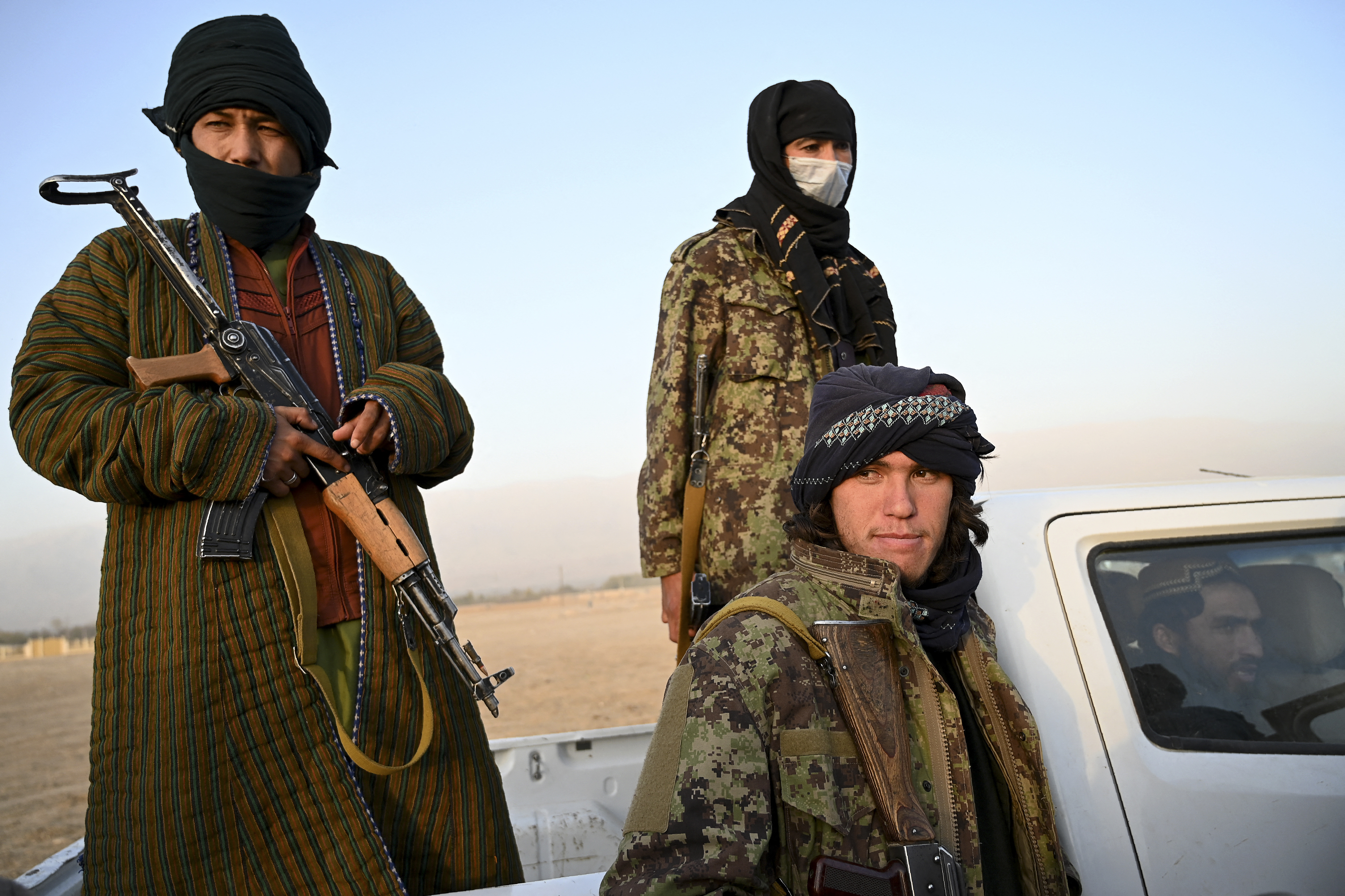 This photo taken on October 29, 2021 shows Taliban fighters standing on the back of a vehicle