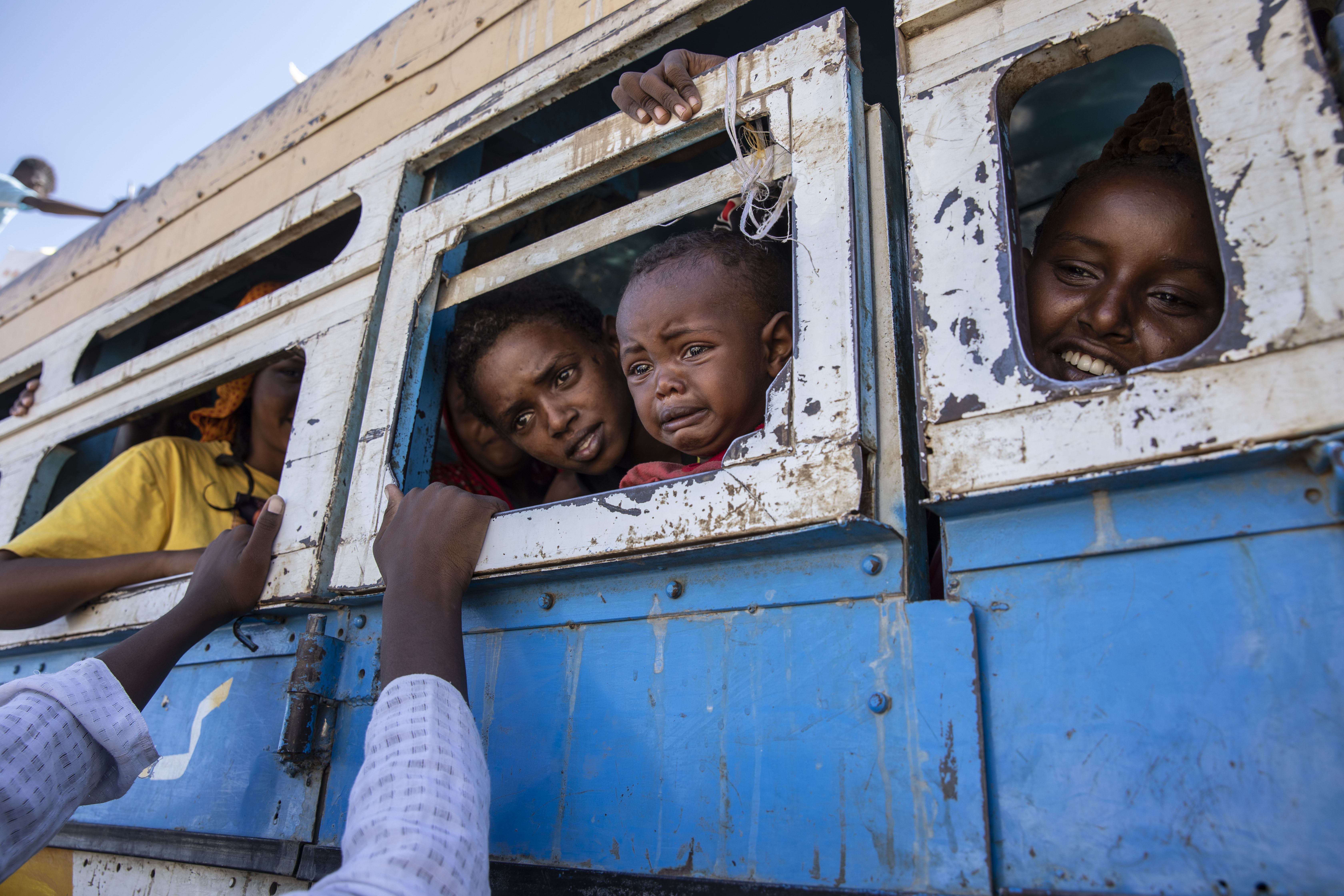 Tigray refugees who fled the conflict in their home region ride a bus going to a temporary shelter, near the Sudan-Ethiopia border, in Hamdayet, eastern Sudan