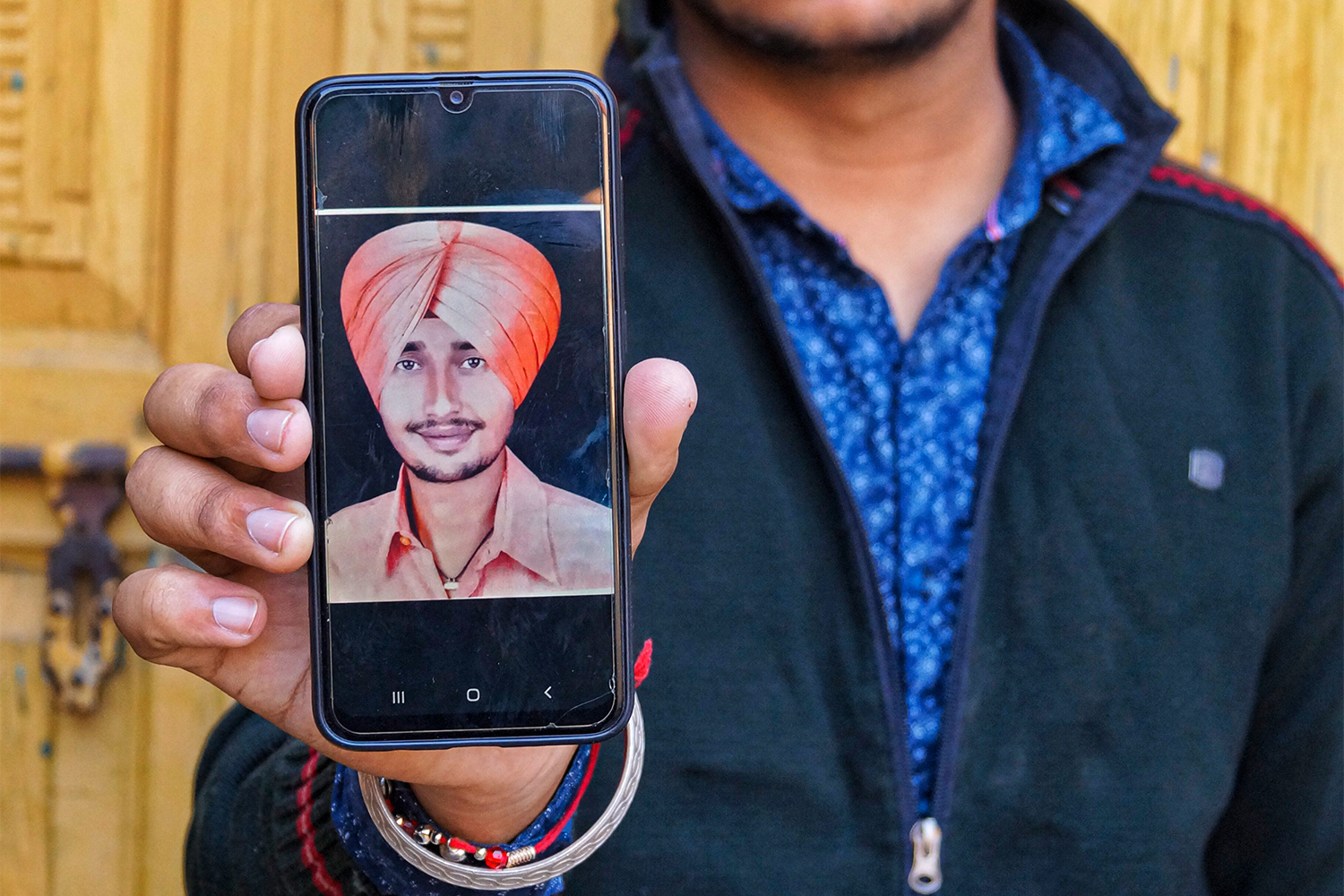 Lovepreet Singh showing a photo of his late father Gurpreet Singh on his mobile phone [Sukhman Billing/Al Jazeera]