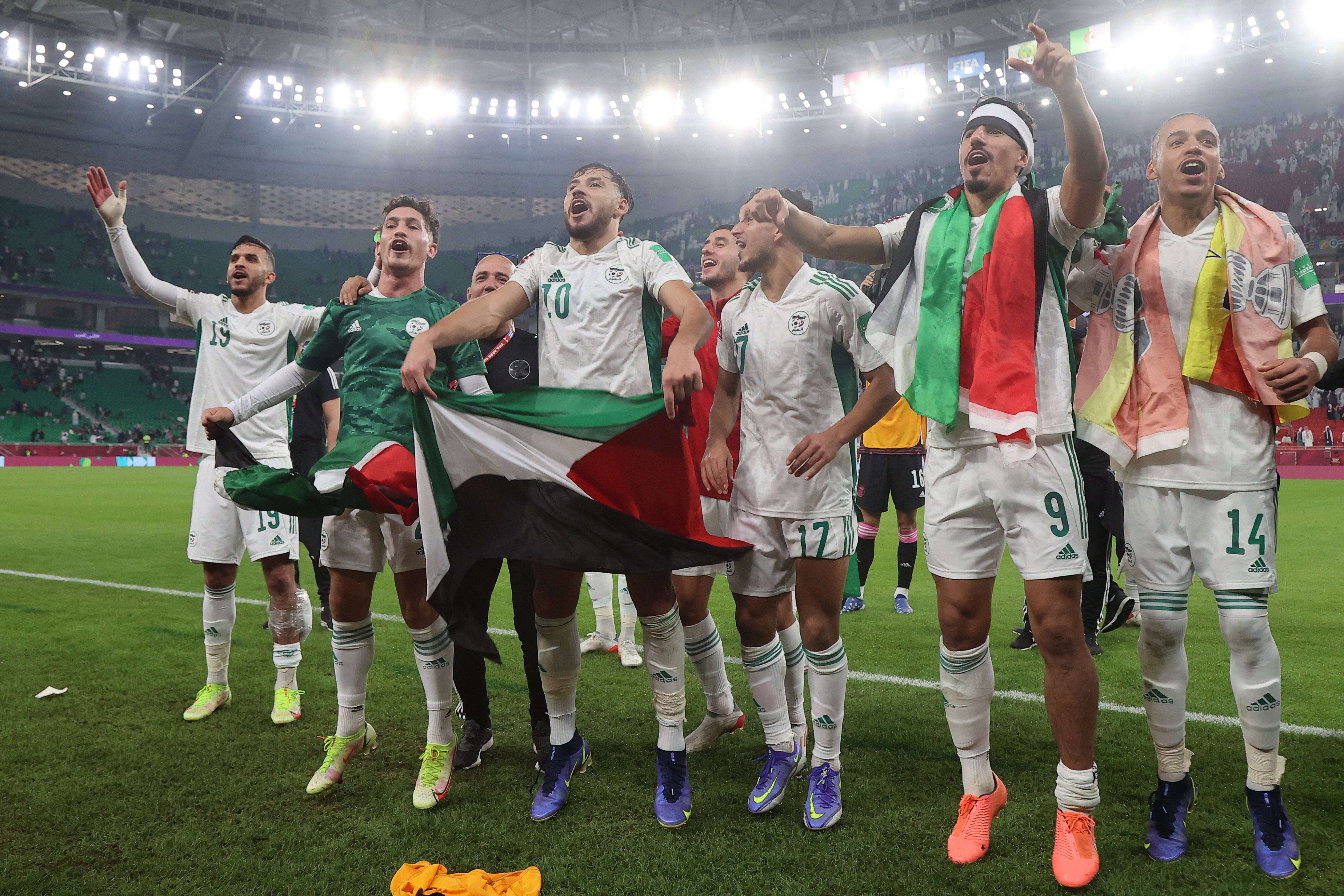 Algeria's players wave Palestinian national flags after winning the FIFA Arab Cup 2021 semi-final football match between Qatar and Algeria at the Al-Thumama Stadium in the Qatari capital of Doha on December 15, 2021 [File: Karim Jaafar/AFP]