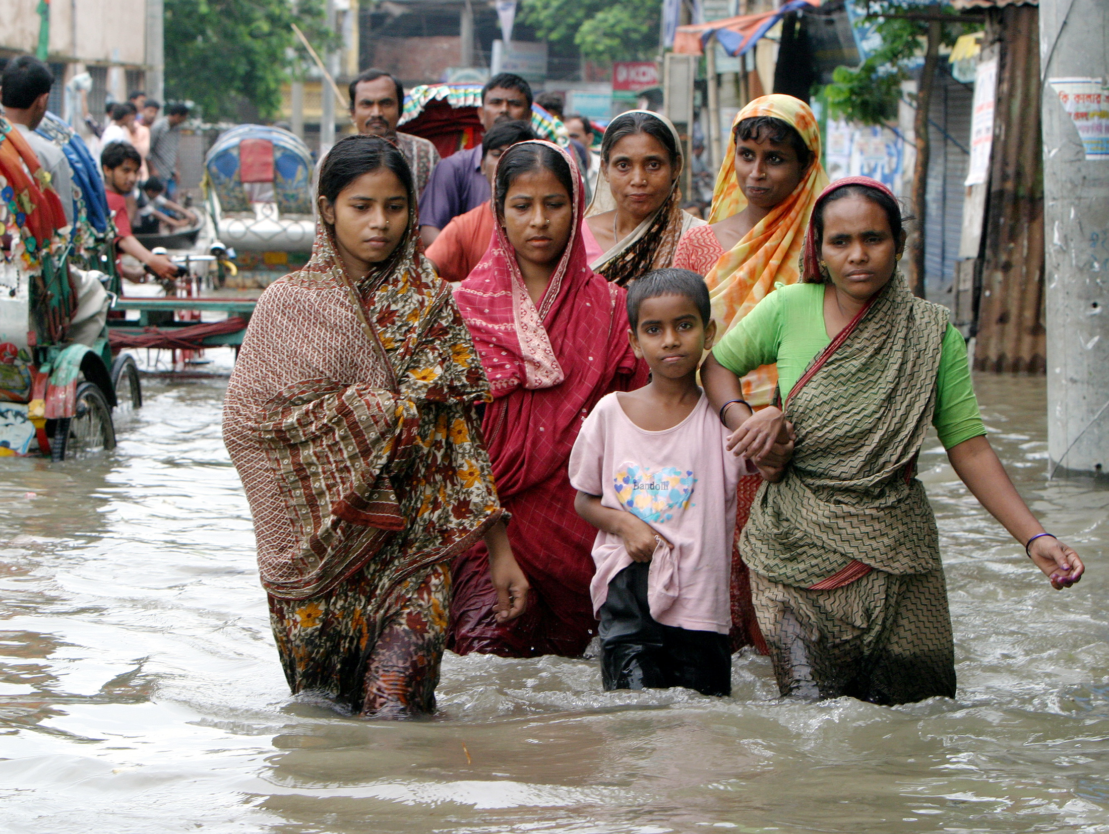 Bangladeshi families wade through a flooded street.