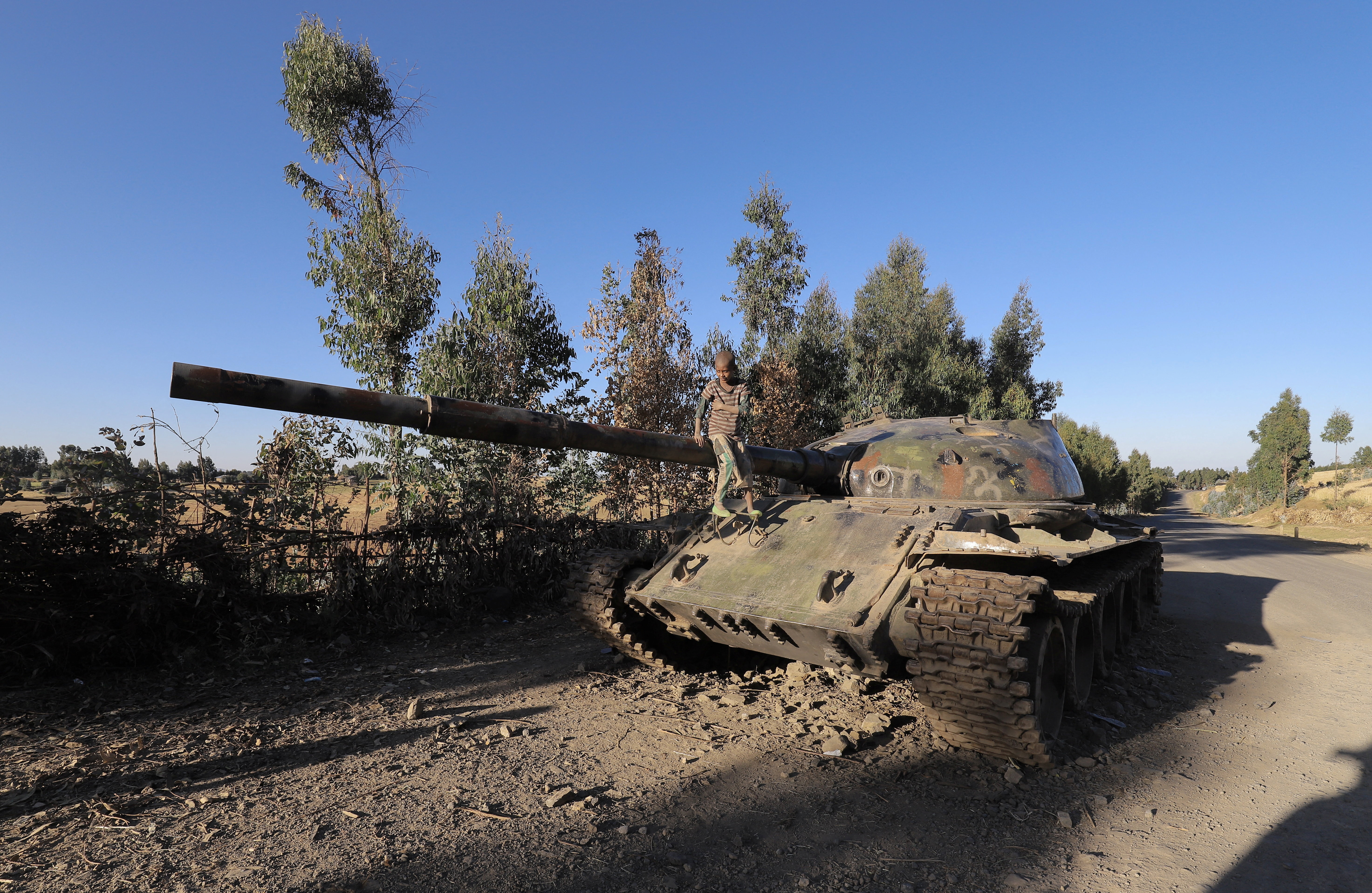 A boy sits on the barrel of a military tank destroyed in Amhara region, Ethiopia