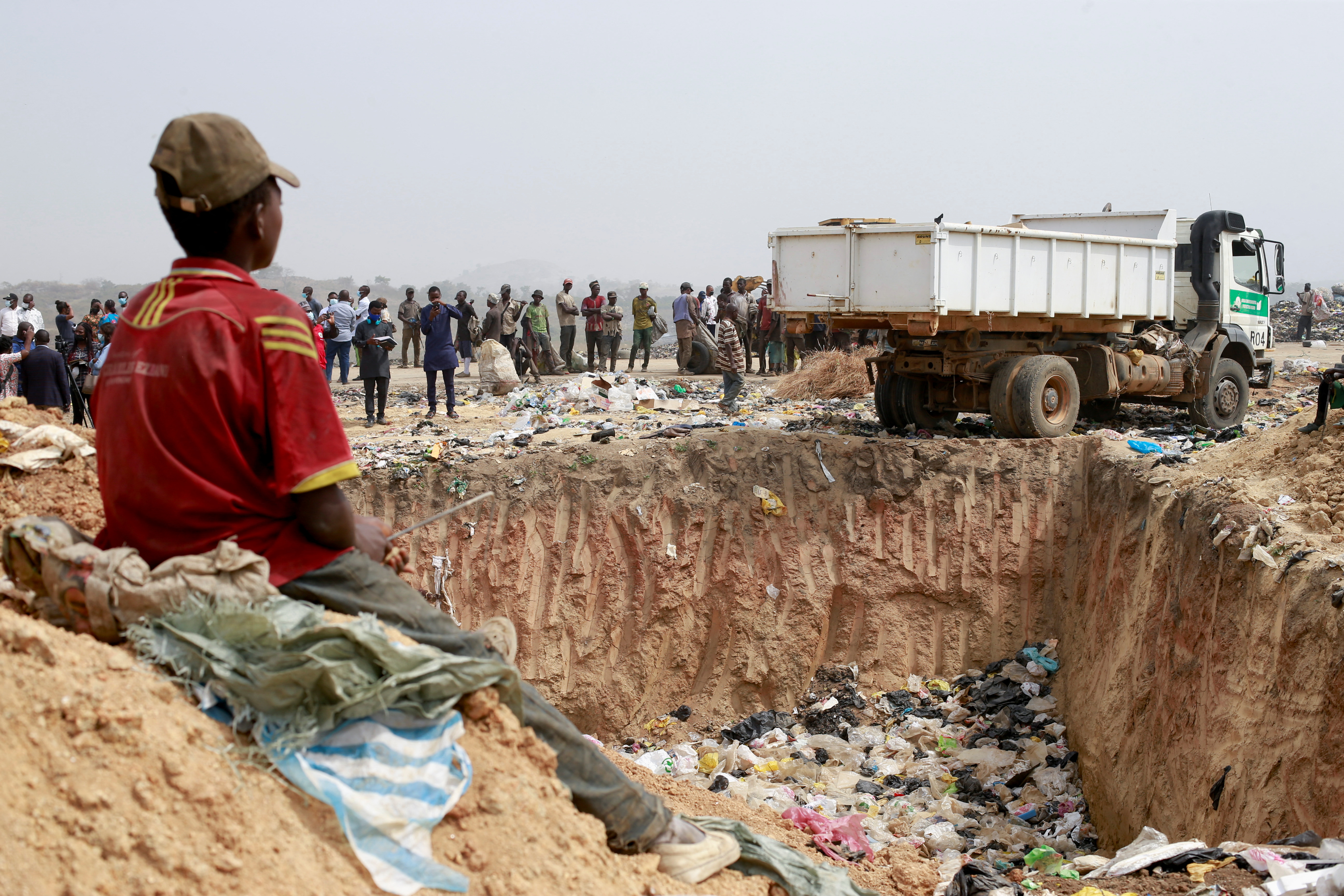 People await the discharge of expired AstraZeneca vaccines at the Gosa dump site in Abuja, Nigeria on December 22, 2021 [Reuters/Afolabi Sotunde]