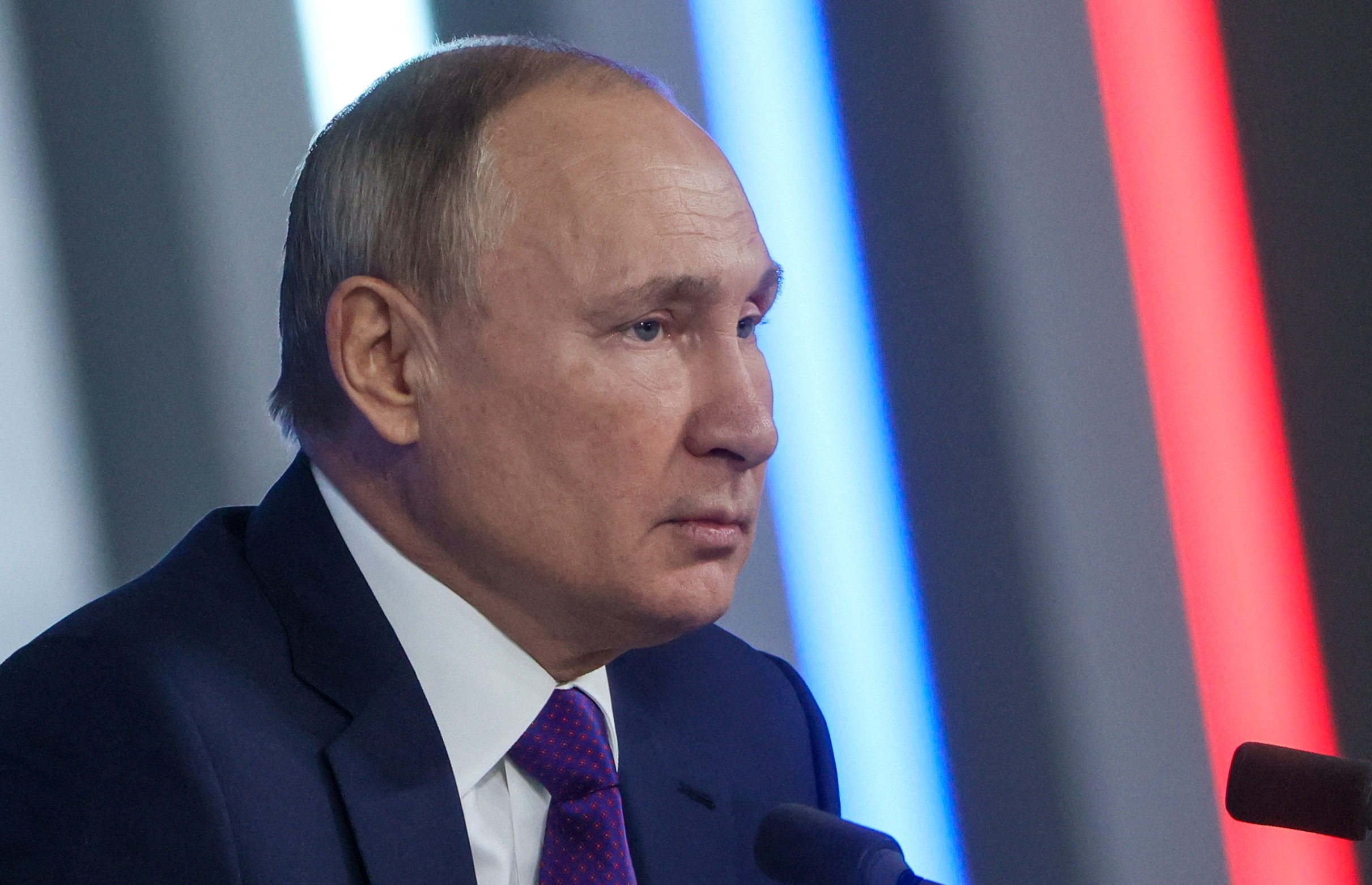 Vladimir Putin answers questions in front of microphones.