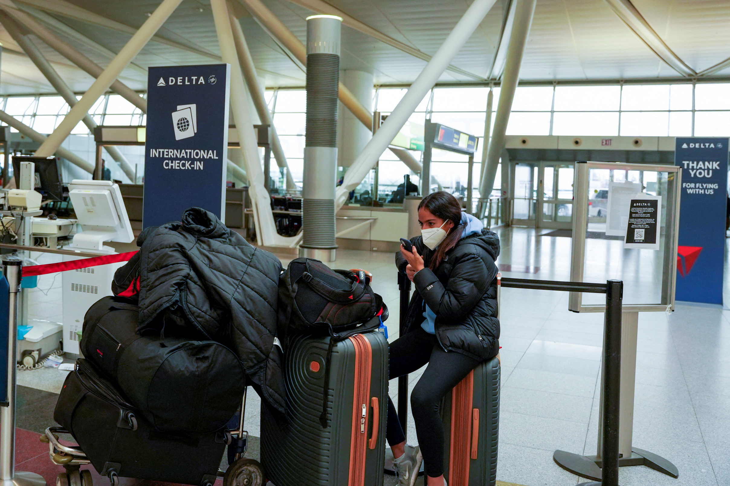 A traveller sits with her luggage in an airport