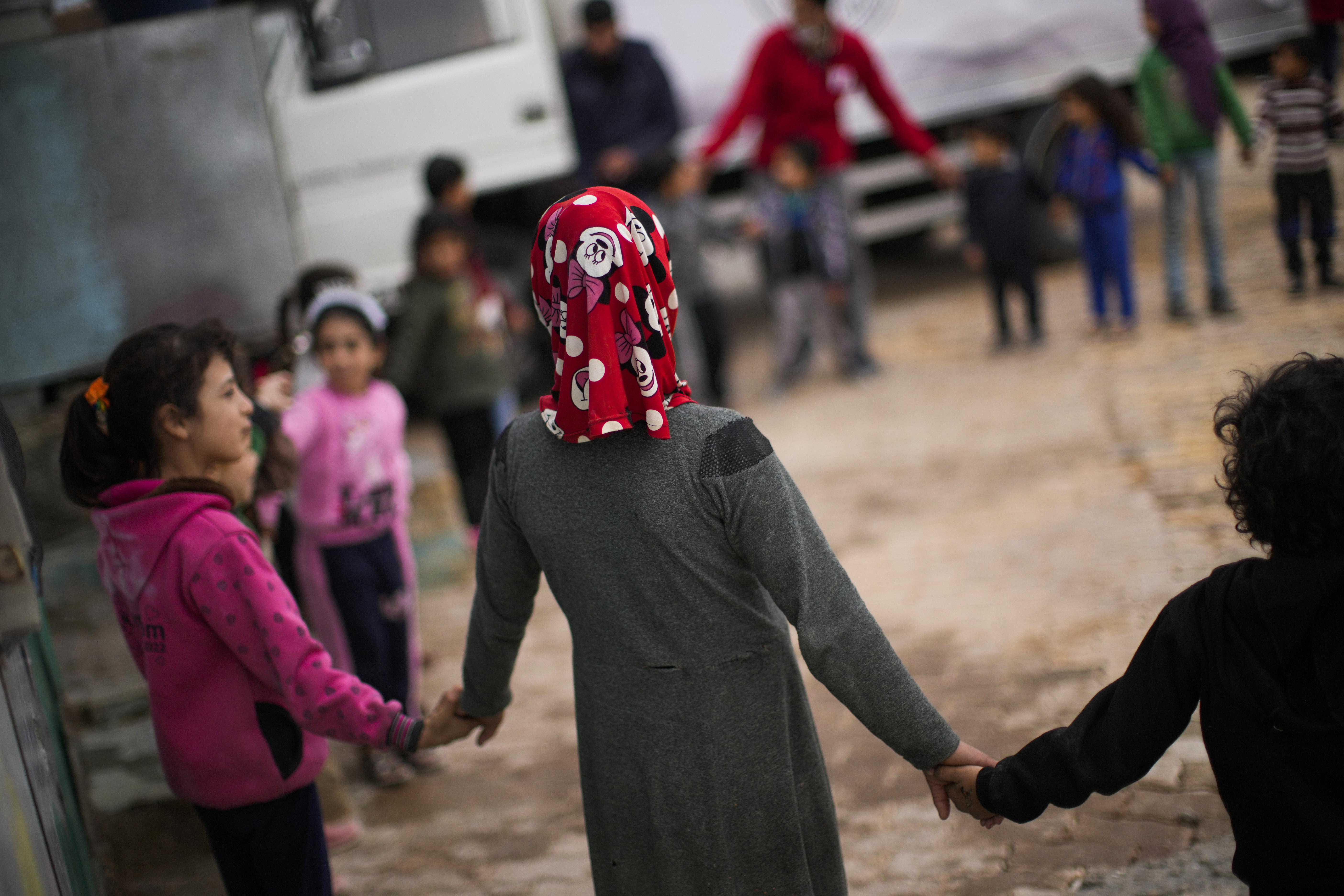 Children hold hands as they wait for aid