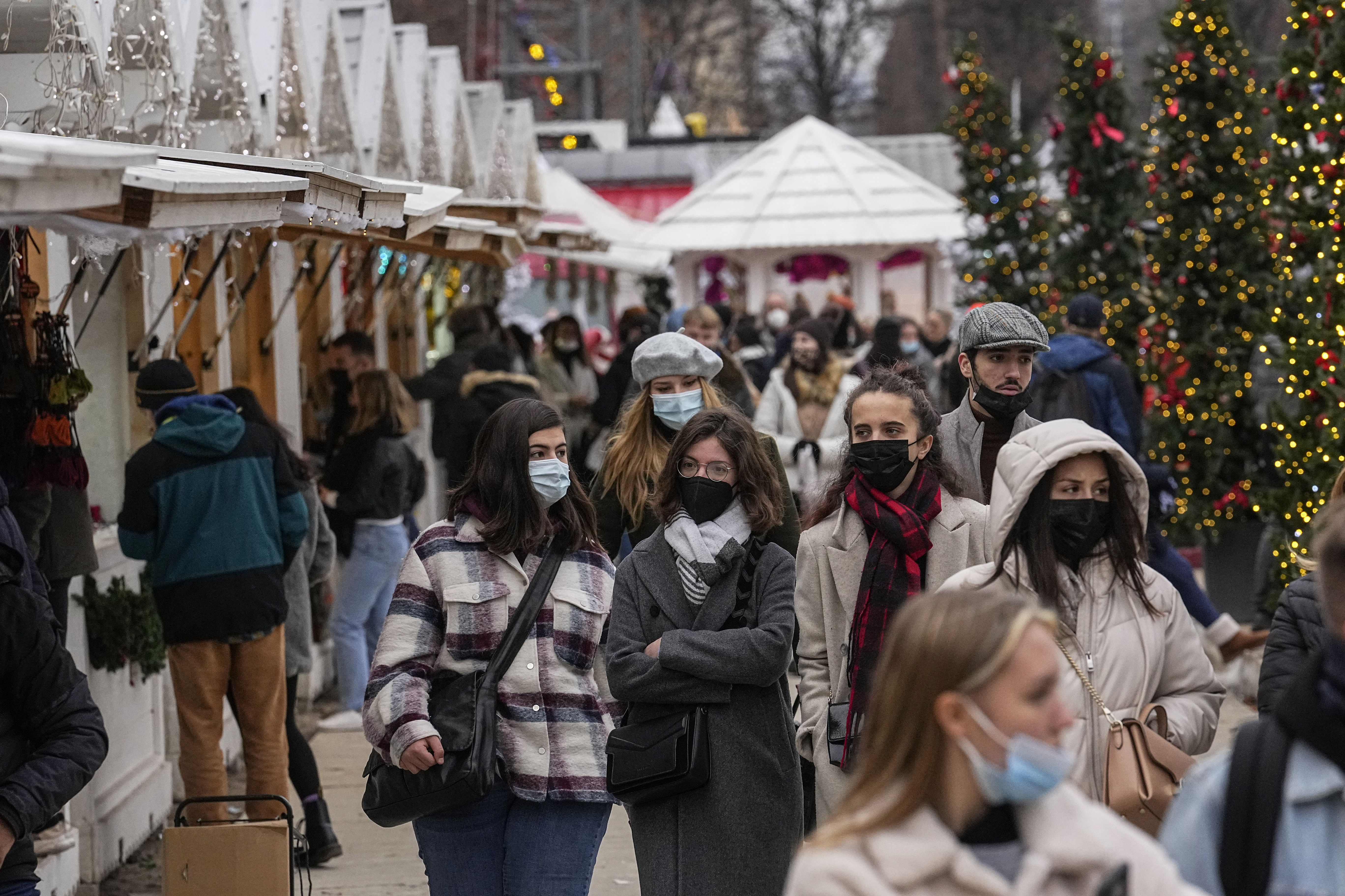 Pedestrians wearing masks are seen walking at an outdoor Christmas market in Paris, France