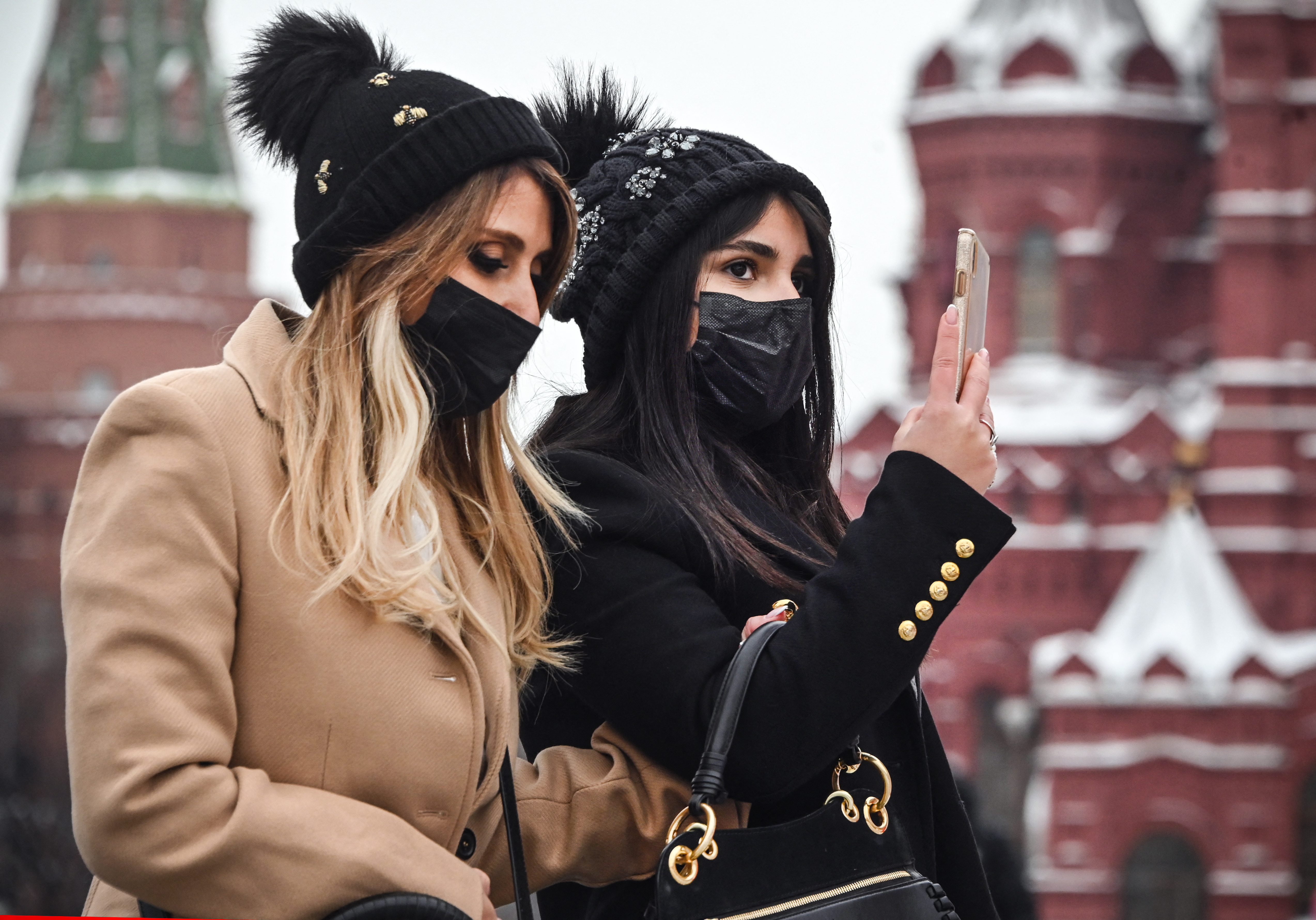 Tourists wearing face masks walk along the Red Square in central Moscow