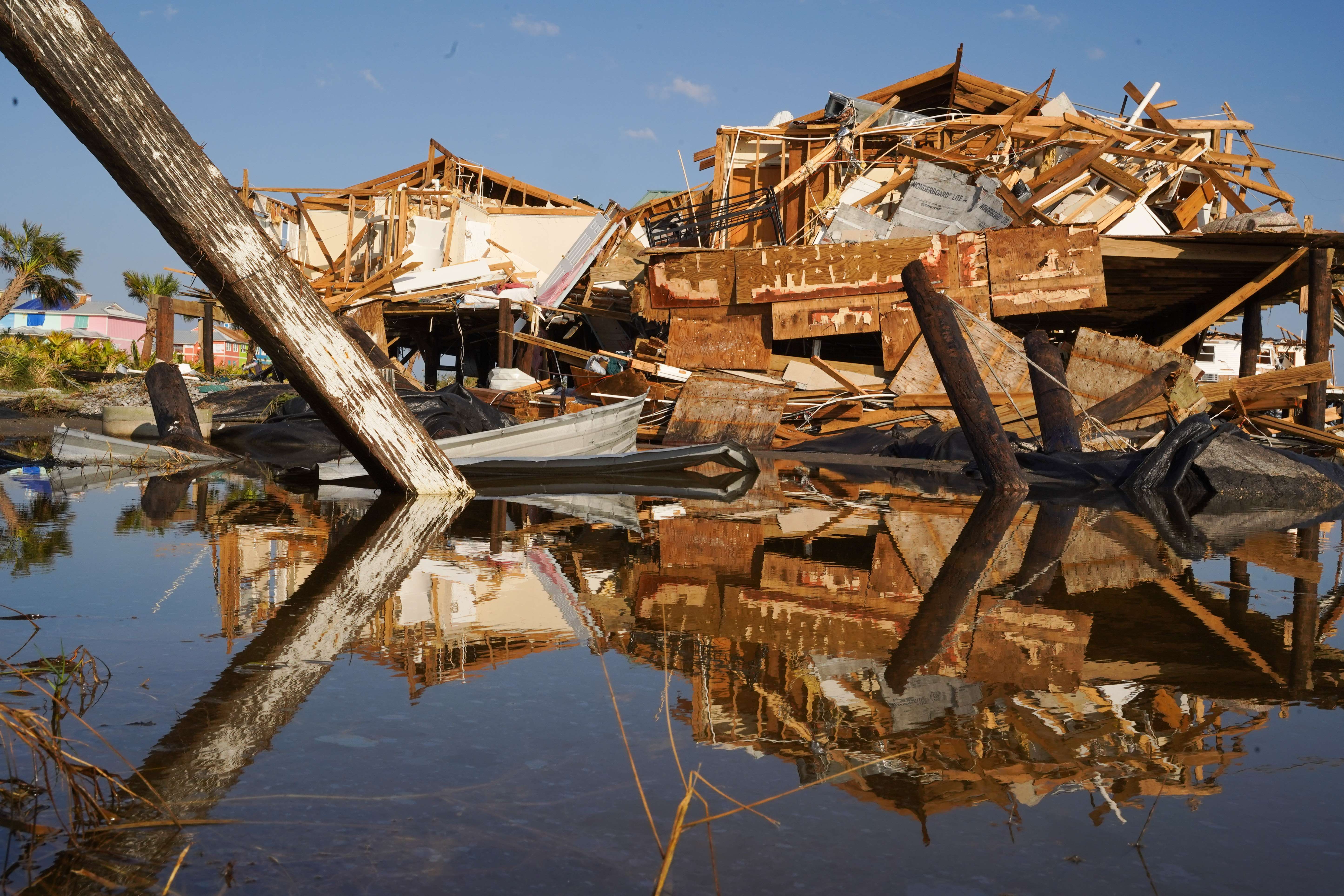 A photo of damaged houses that have fallen apart by the sea.