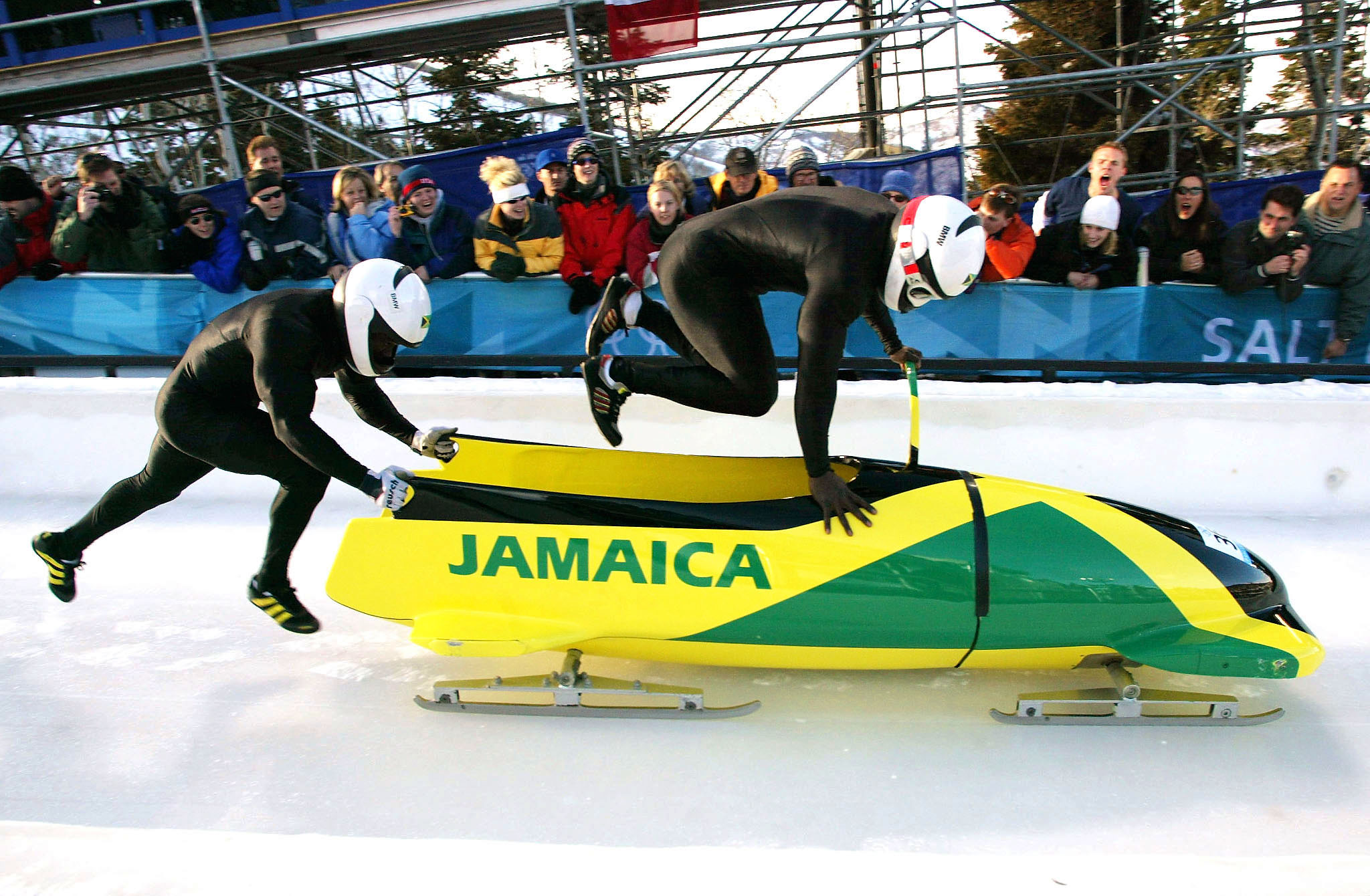Lascelles Oneil Brown (L) and Winston Alexander Watt of the Jamaica-1 team leap into their sled at the start of heat three of the two-man bobsleigh competition at the Salt Lake 2002 Winter Olympic Games, February 17, 2002 in Park City