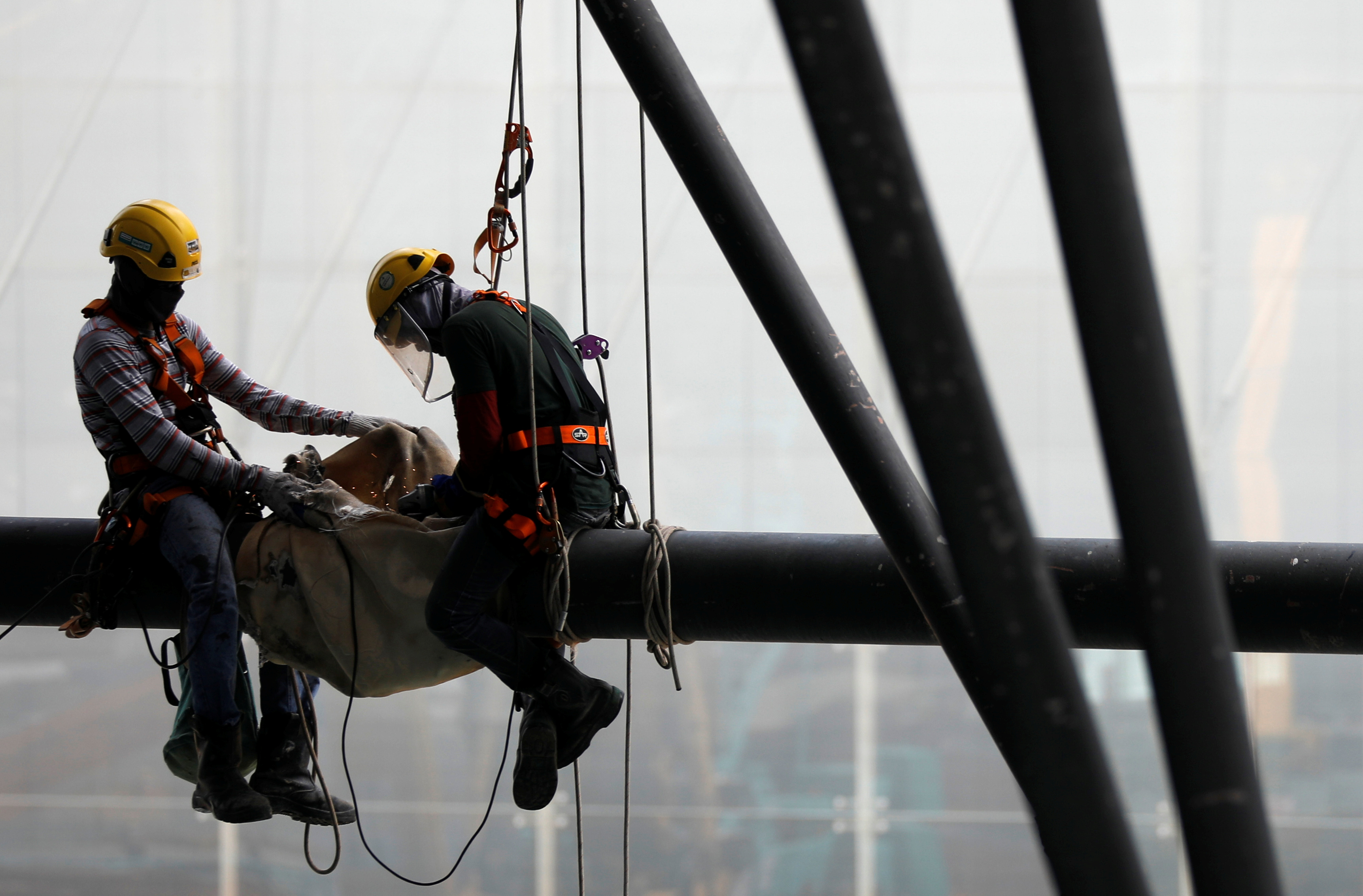 Construction workers on a steel beam at a work site in Singapore.