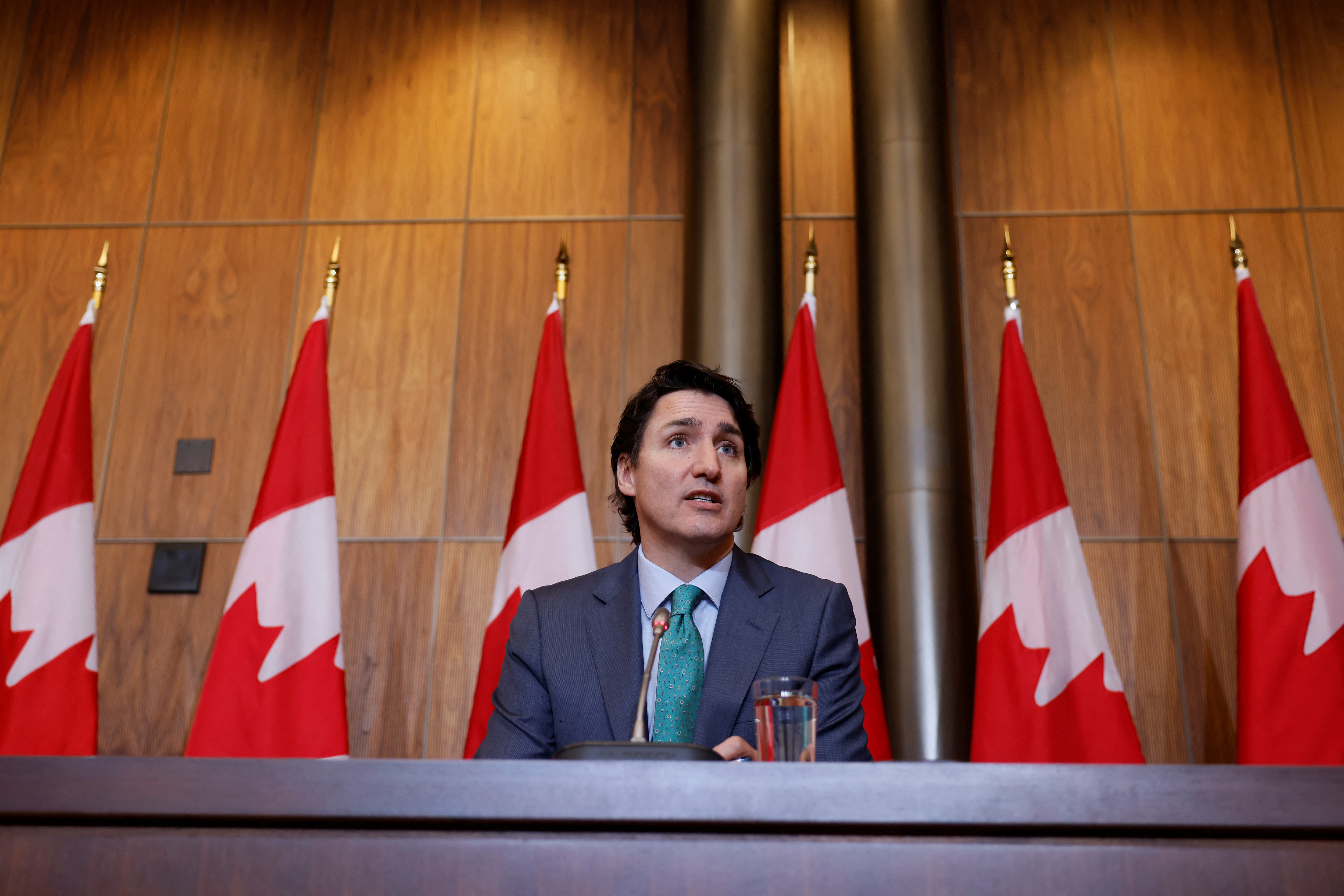 Canada's Prime Minister Justin Trudeau takes part in a news conference sitting behind a table with Canadian flags seen in the background