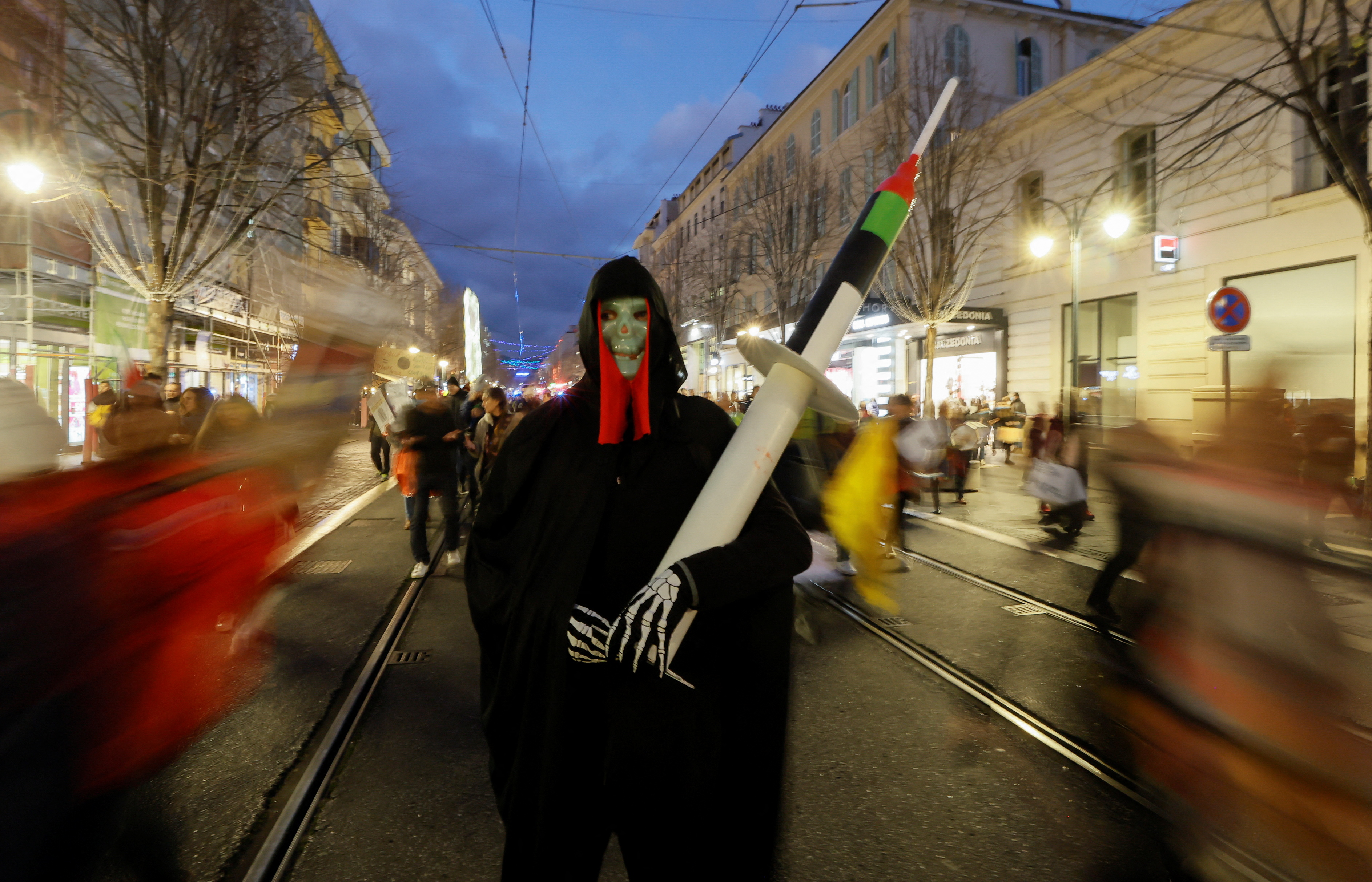 A man wearing a death mask, holds a mock-up syringe during a demonstration to protest against a bill that would transform France's current coronavirus disease (COVID-19) health pass into a "vaccine pass", in Nice, France