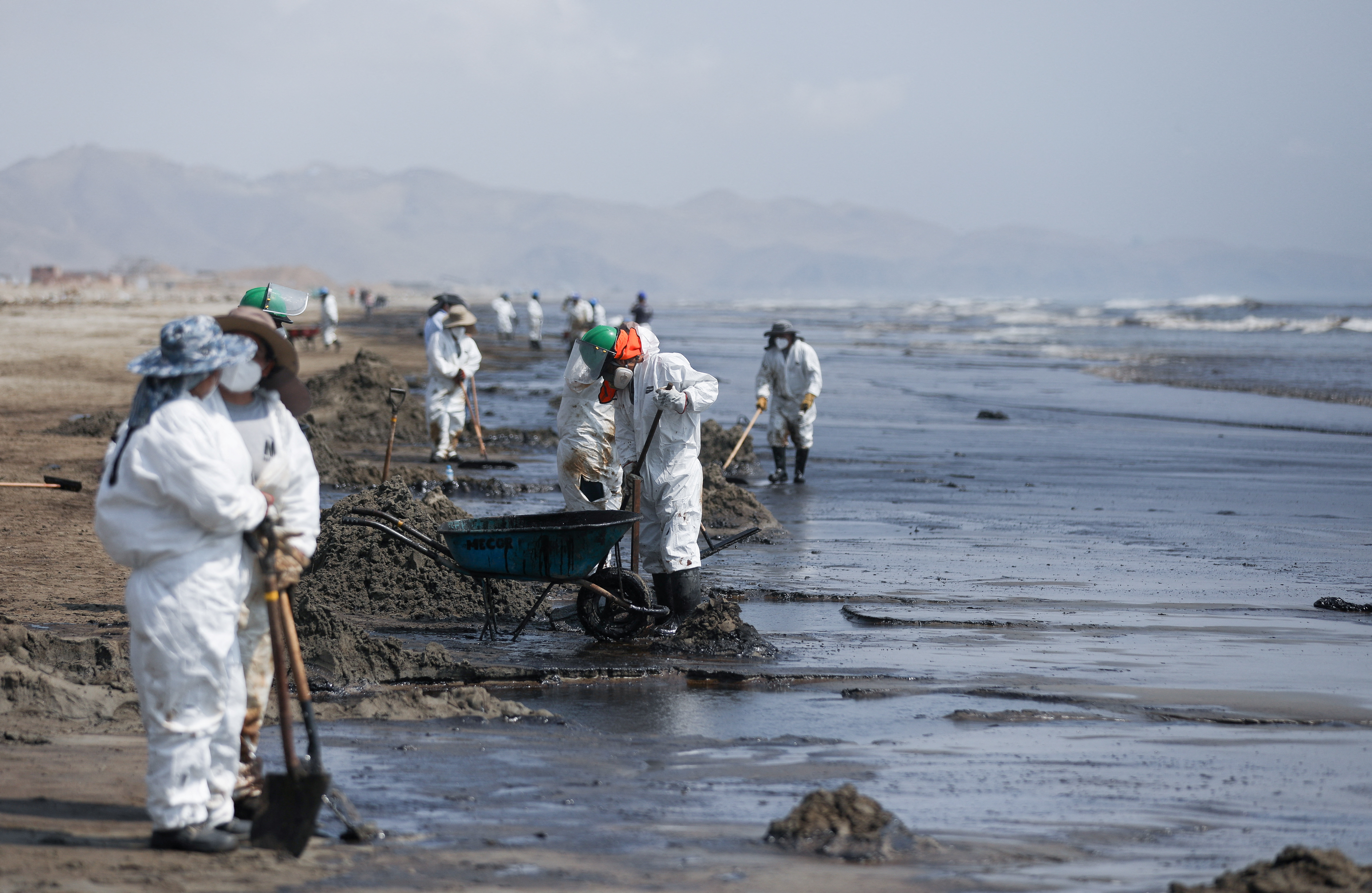 Workers clean up an oil spill caused by abnormal waves in Ventanilla, Peru