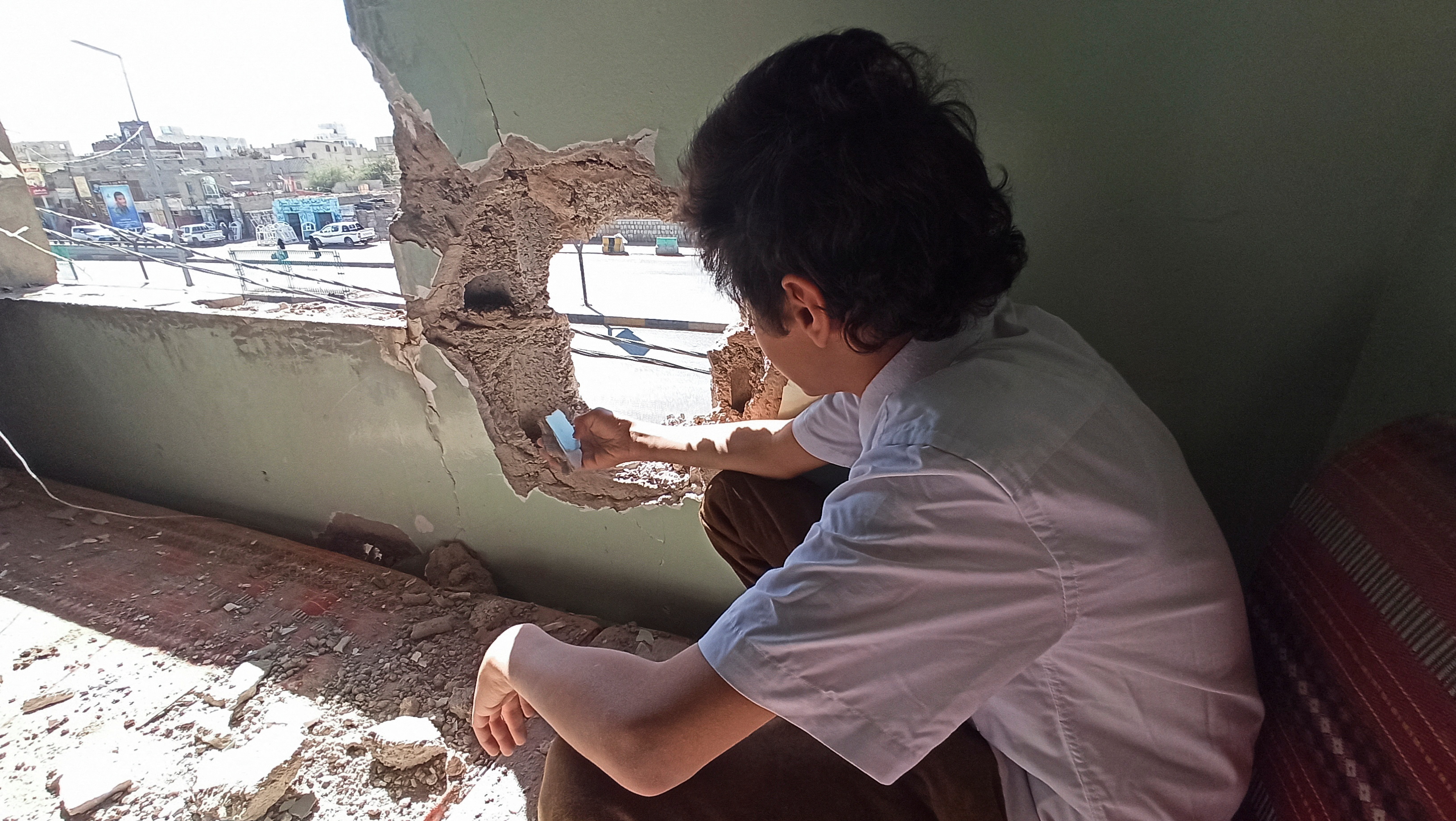 A boy looks through a hole in the wall caused by air strikes in Sanaa, Yemen.