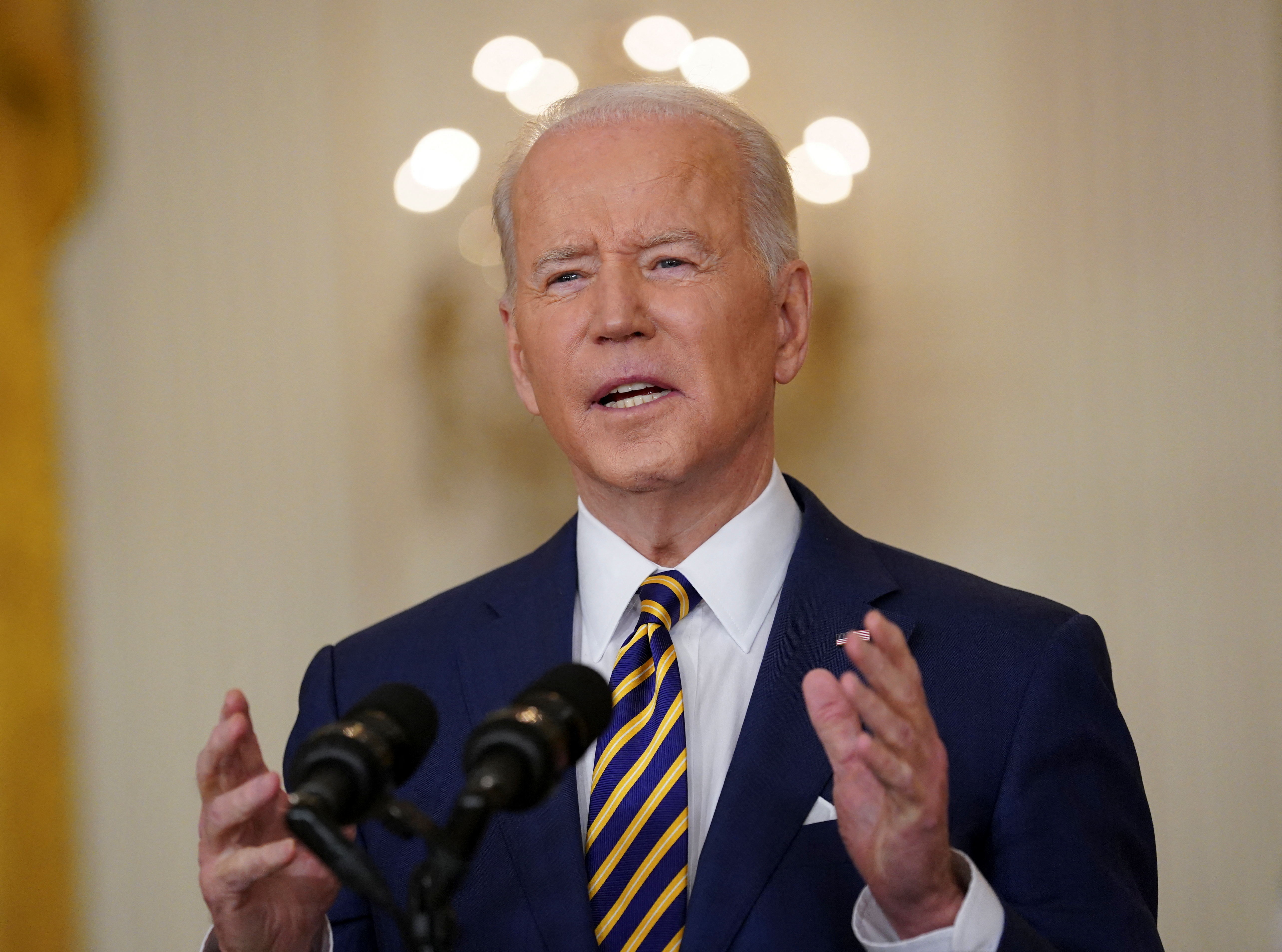 Joe Biden stands at a podium to deliver a speech on eve of one-year mark of his presidency