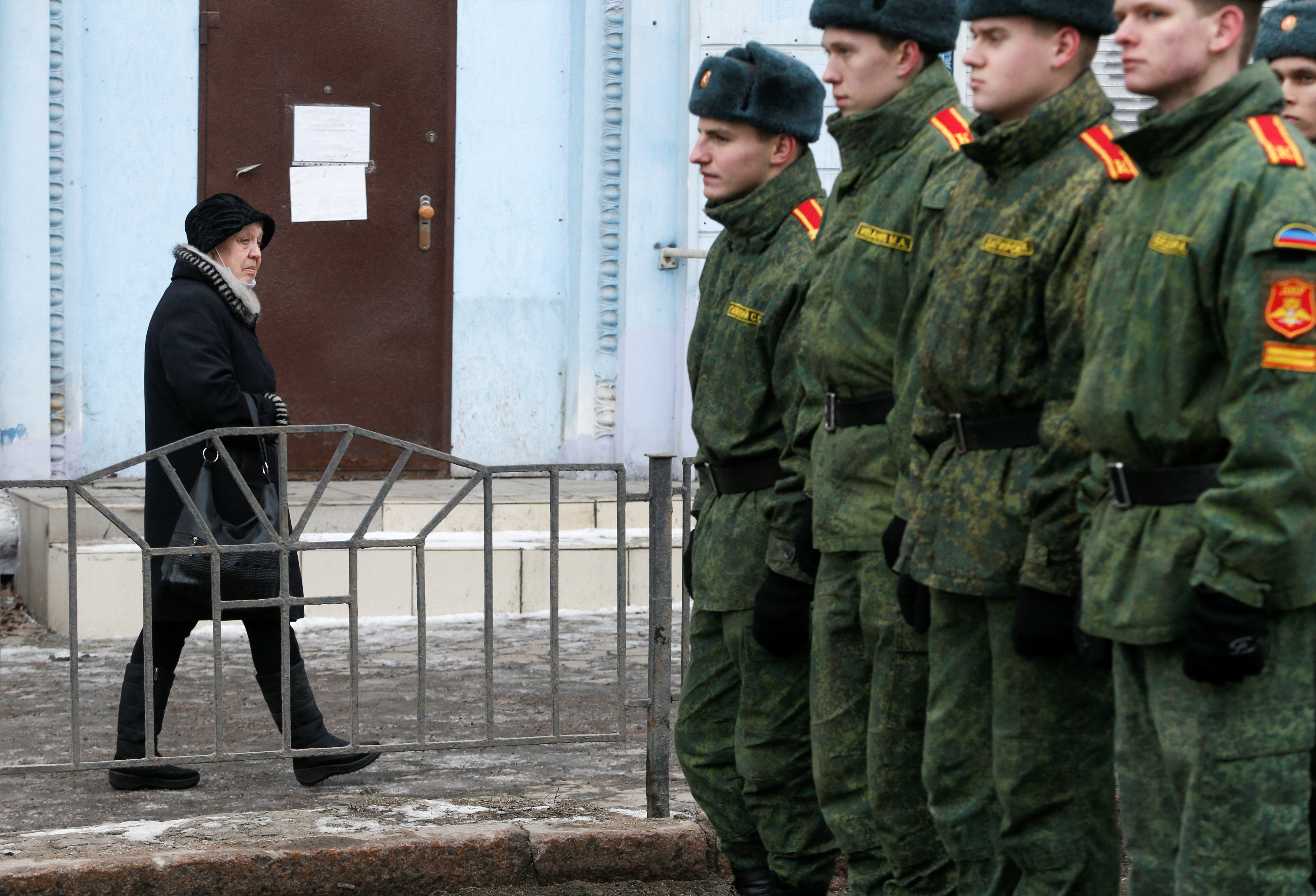 A woman walks past cadets of the self-proclaimed Donetsk People's Republic