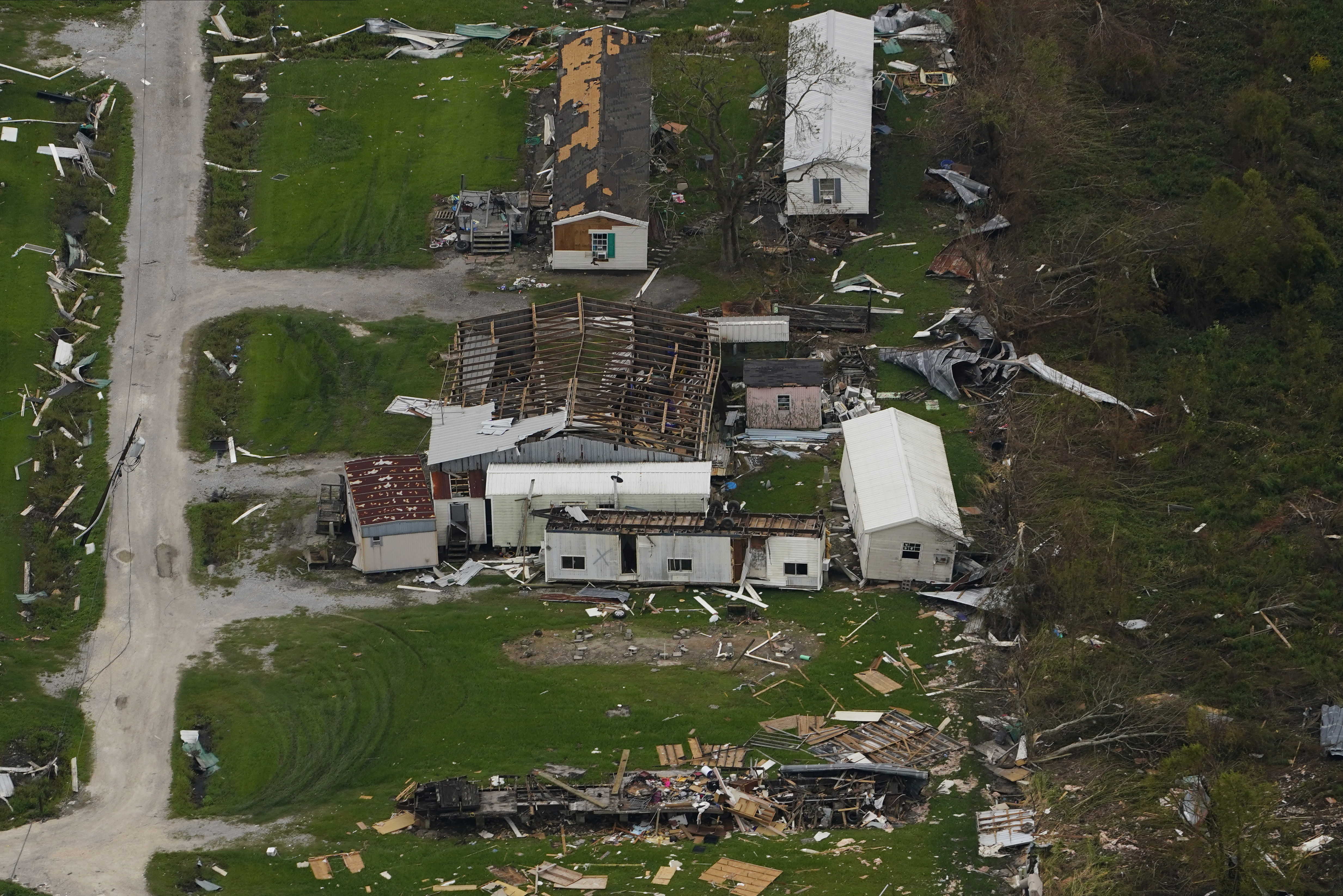 An aerial photo of the remains of homes that have been destroyed with grass all around.