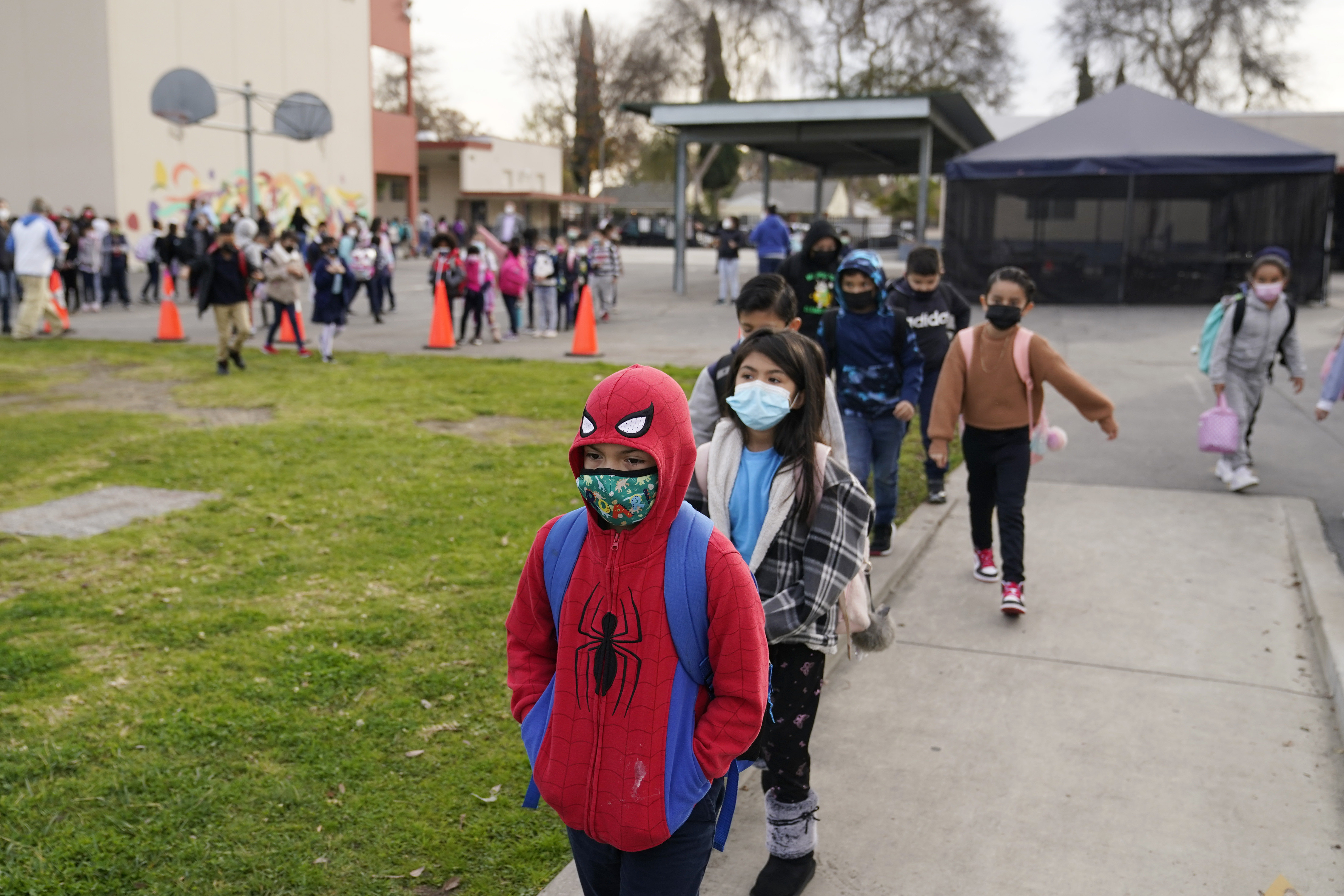 Masked Children walk towards school building