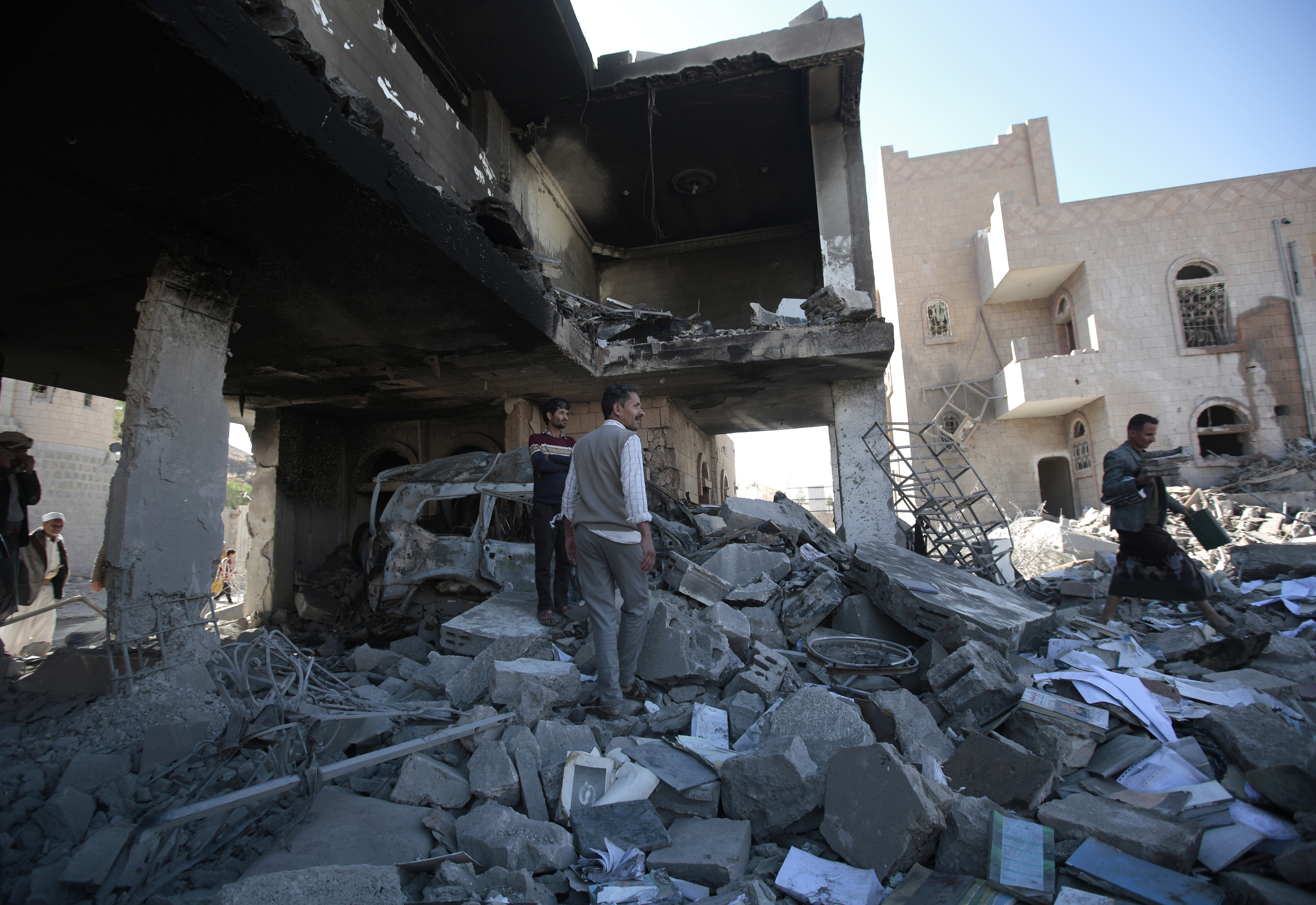 People inspect the wreckage of buildings damaged by Saudi-led coalition airstrikes in Sanaa