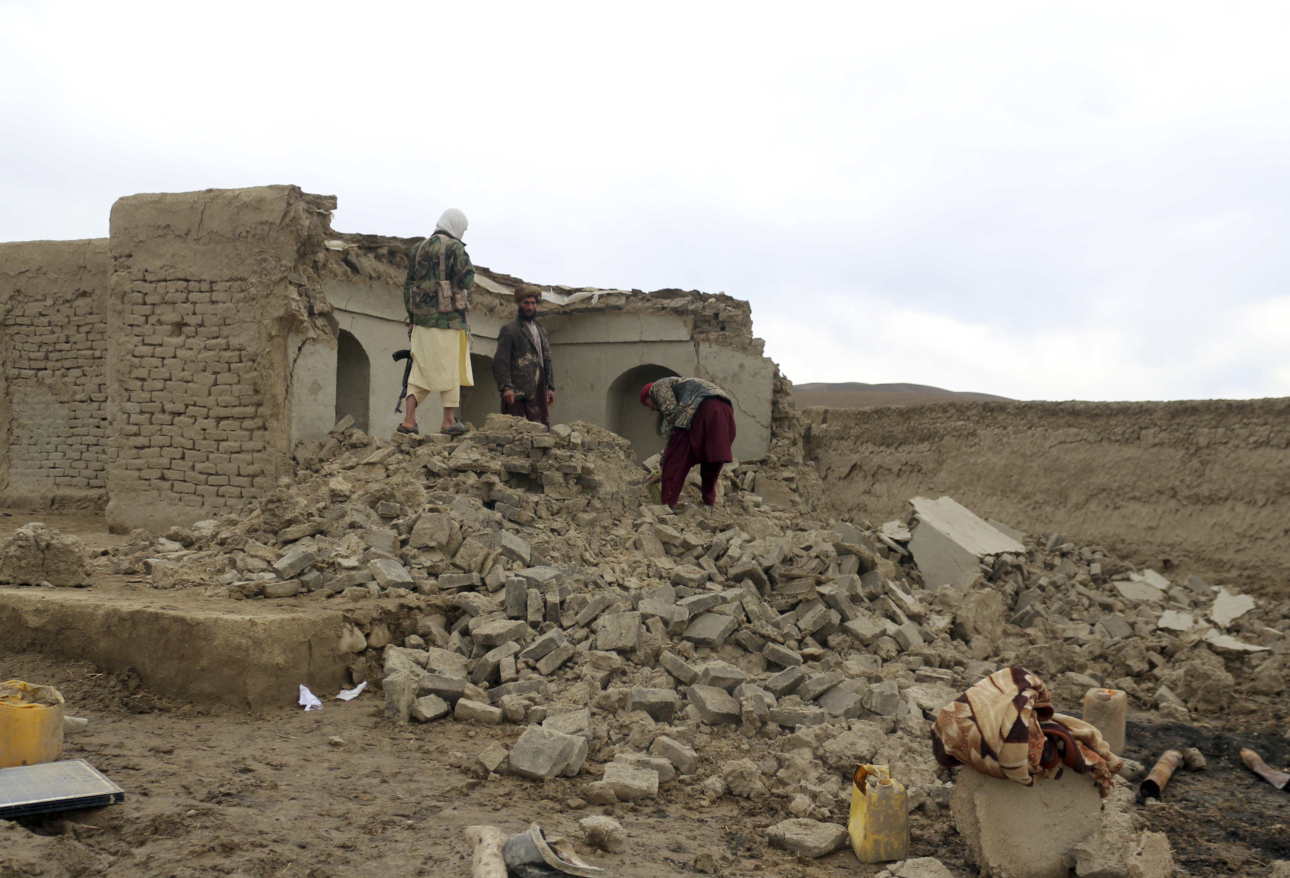 Afghan villagers remove bricks after their home was damaged by earthquake