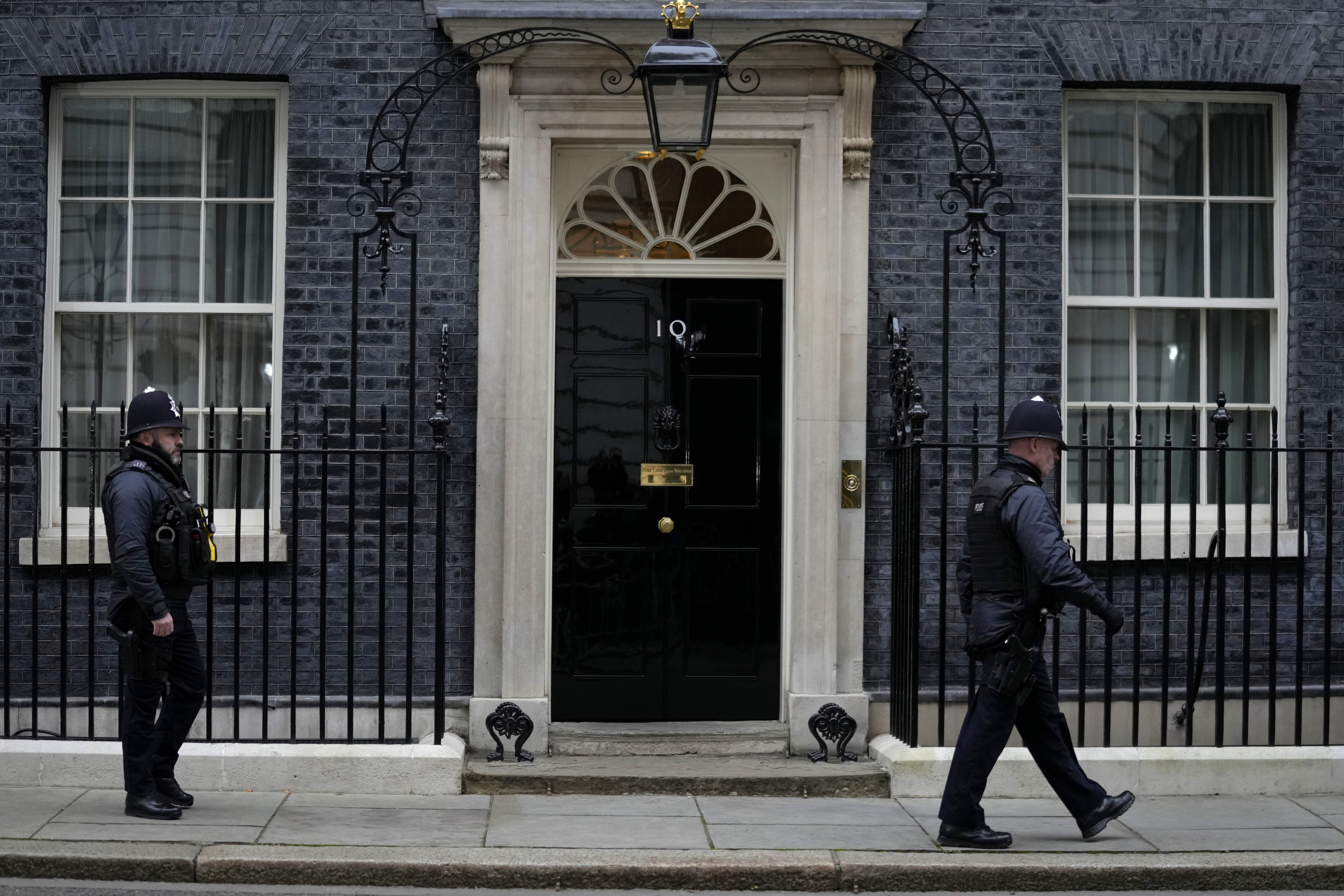 Two metropolitan police officers walk past 10 Downing Street in London