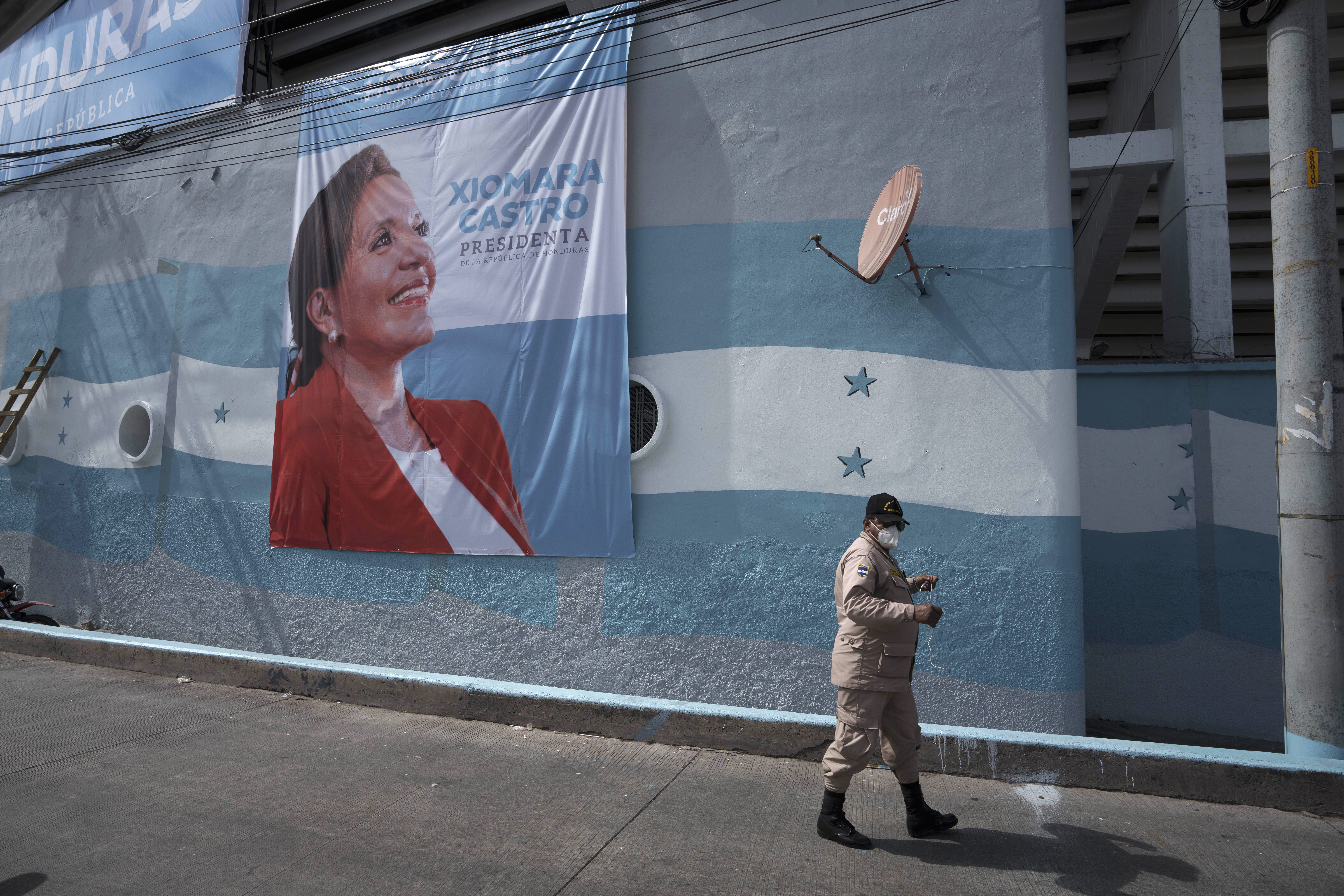 Man walking past banner of Xiomara Castro