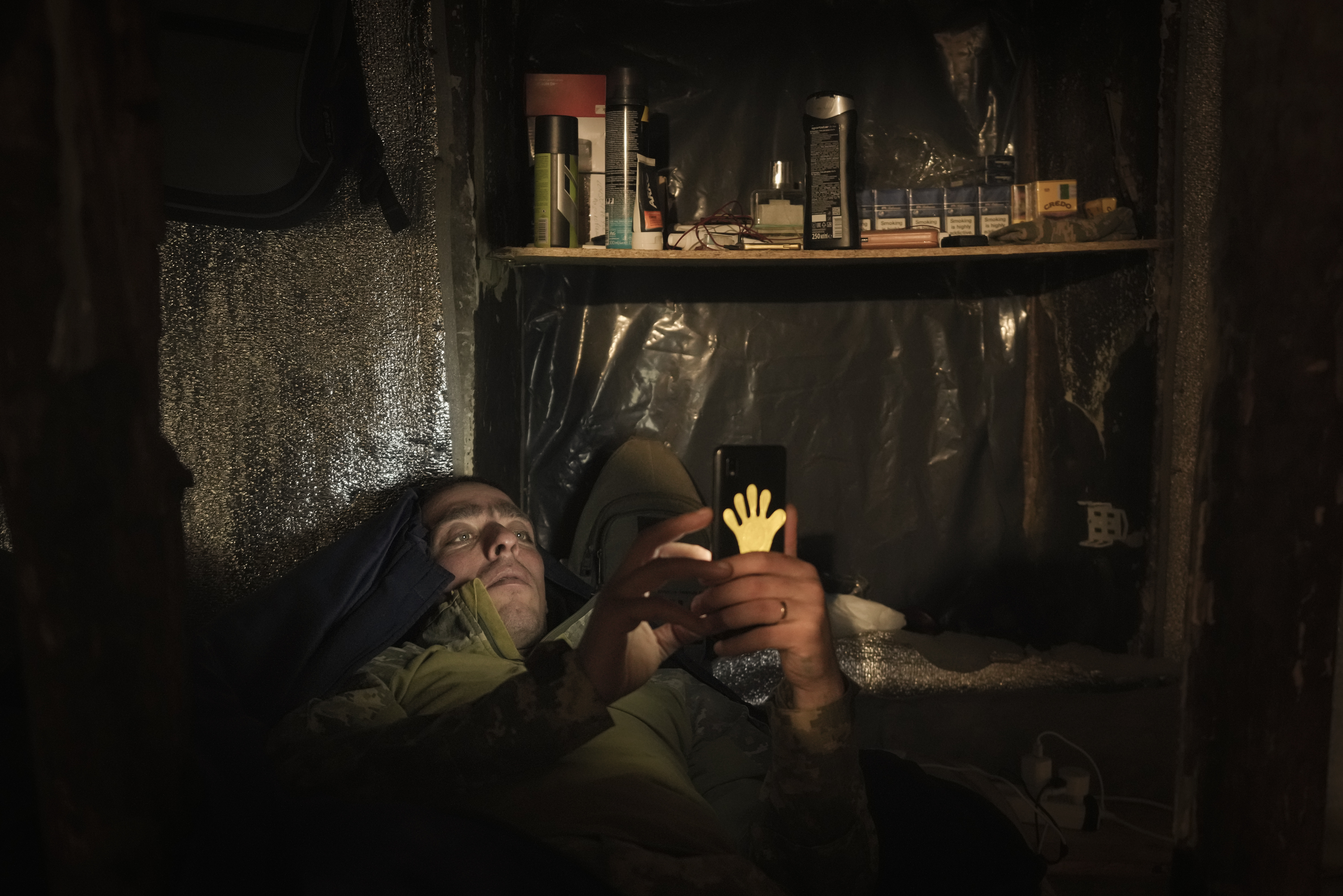 A Ukrainian serviceman lies in bed looking at a mobile phone at a front line position in the Luhansk area, eastern Ukraine, Friday, Jan. 28, 2022.