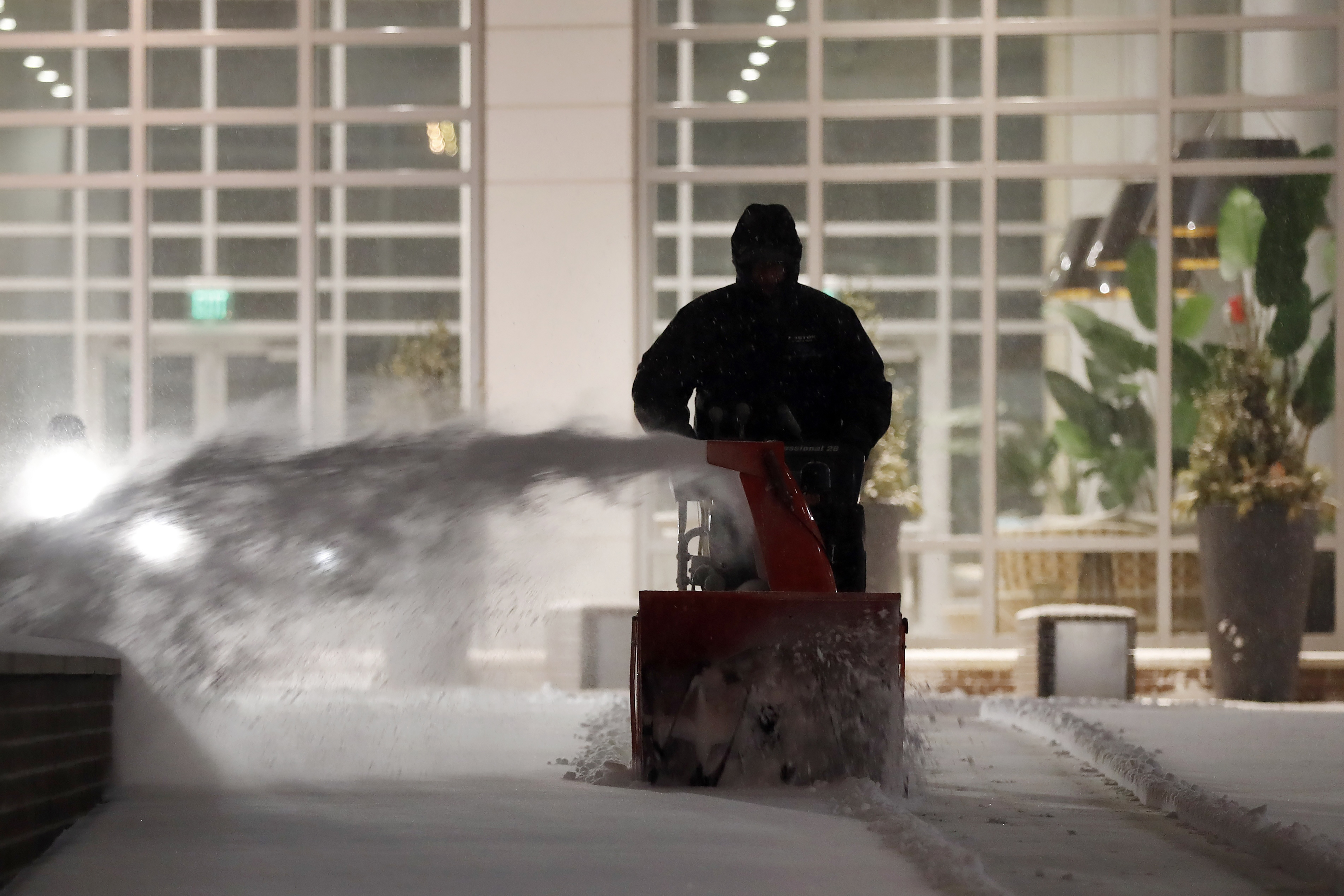 A worker clears the sidewalk at East Pier in the East Boston neighborhood of Boston, Saturday, Jan. 29, 2022