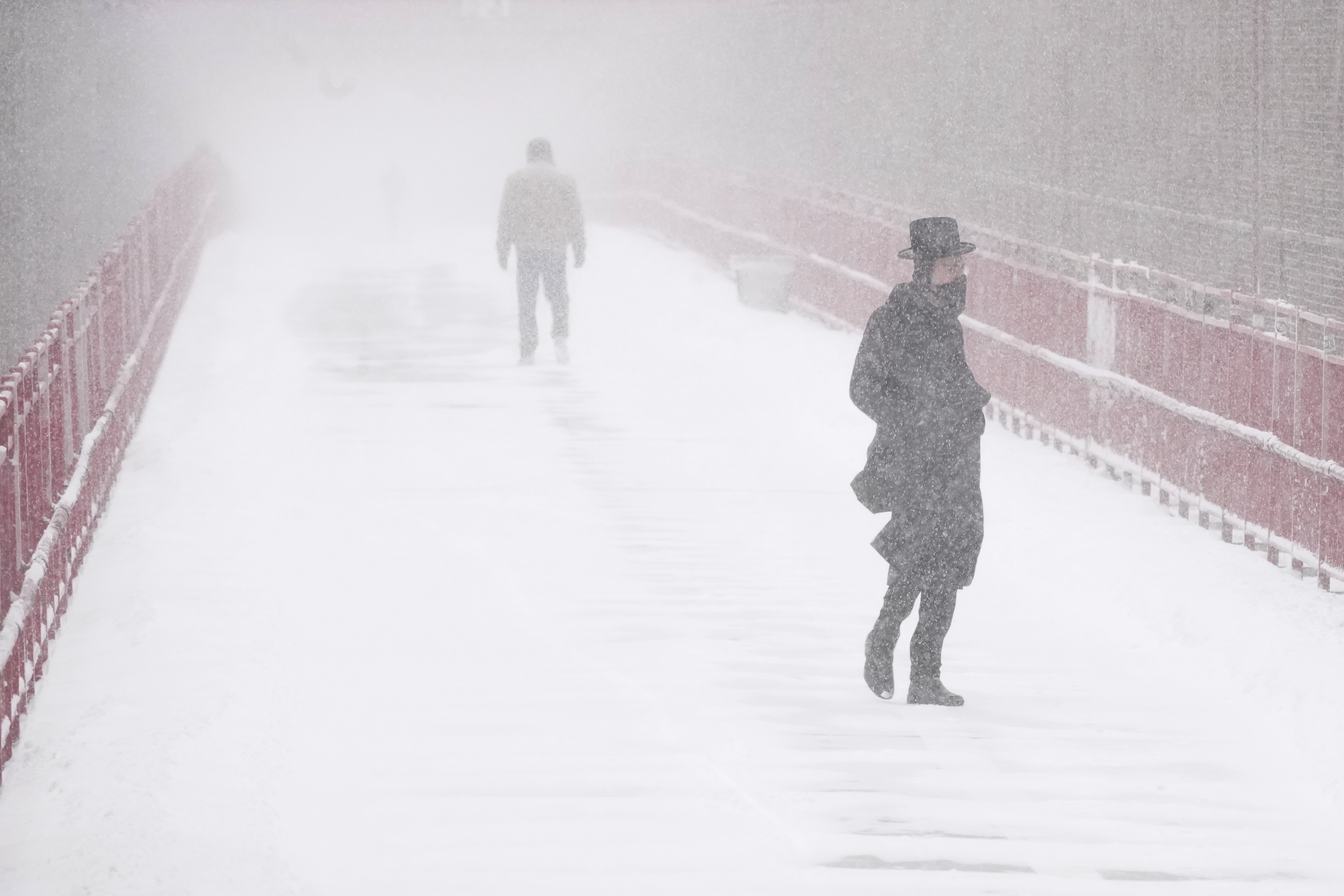 People make their way over the Williamsburg bridge during a snow storm, Saturday, Jan. 29, 2022, in New York