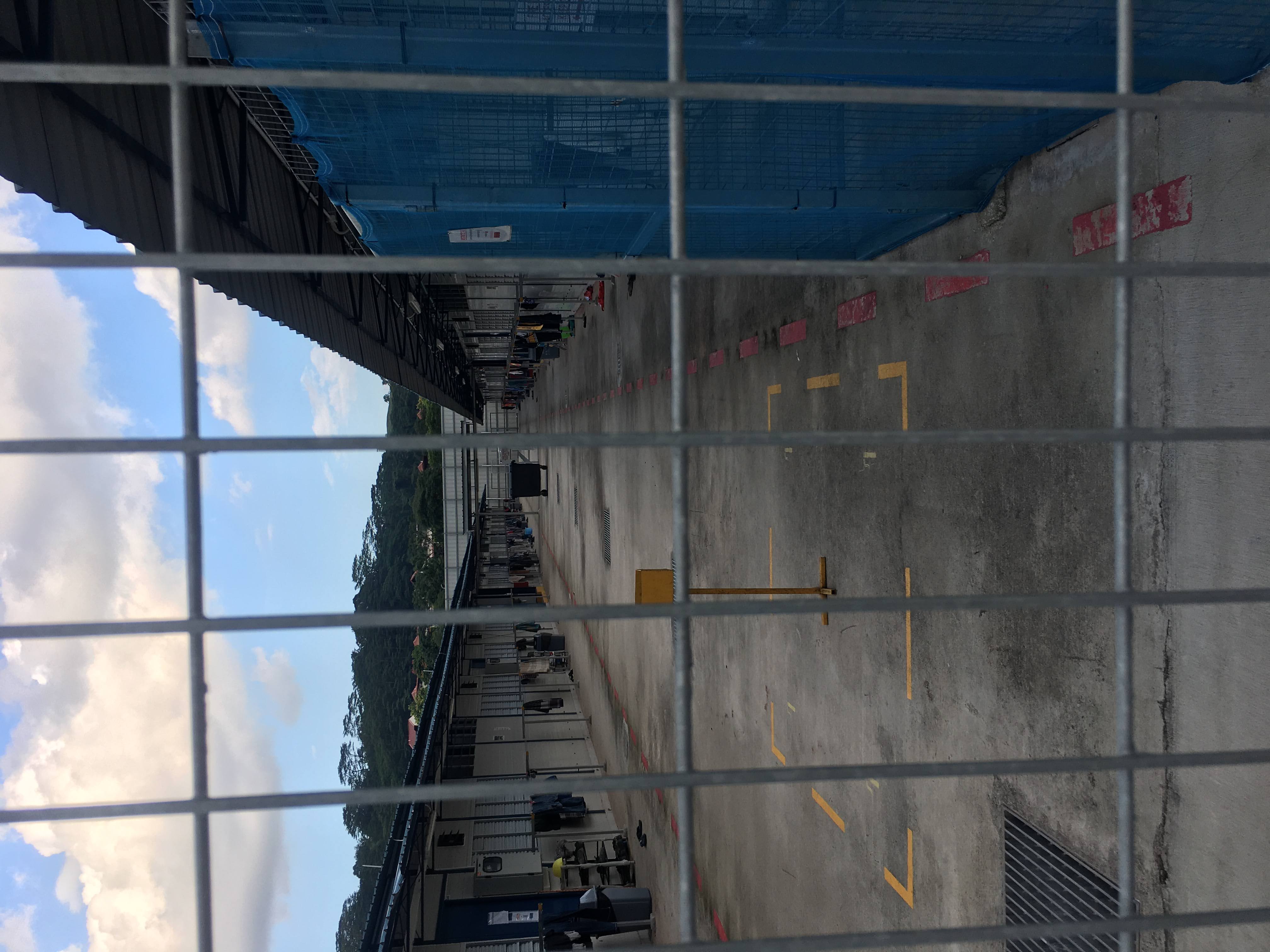 The workers dormitories overlooking a wide concrete walkway seen through a wire fencthe