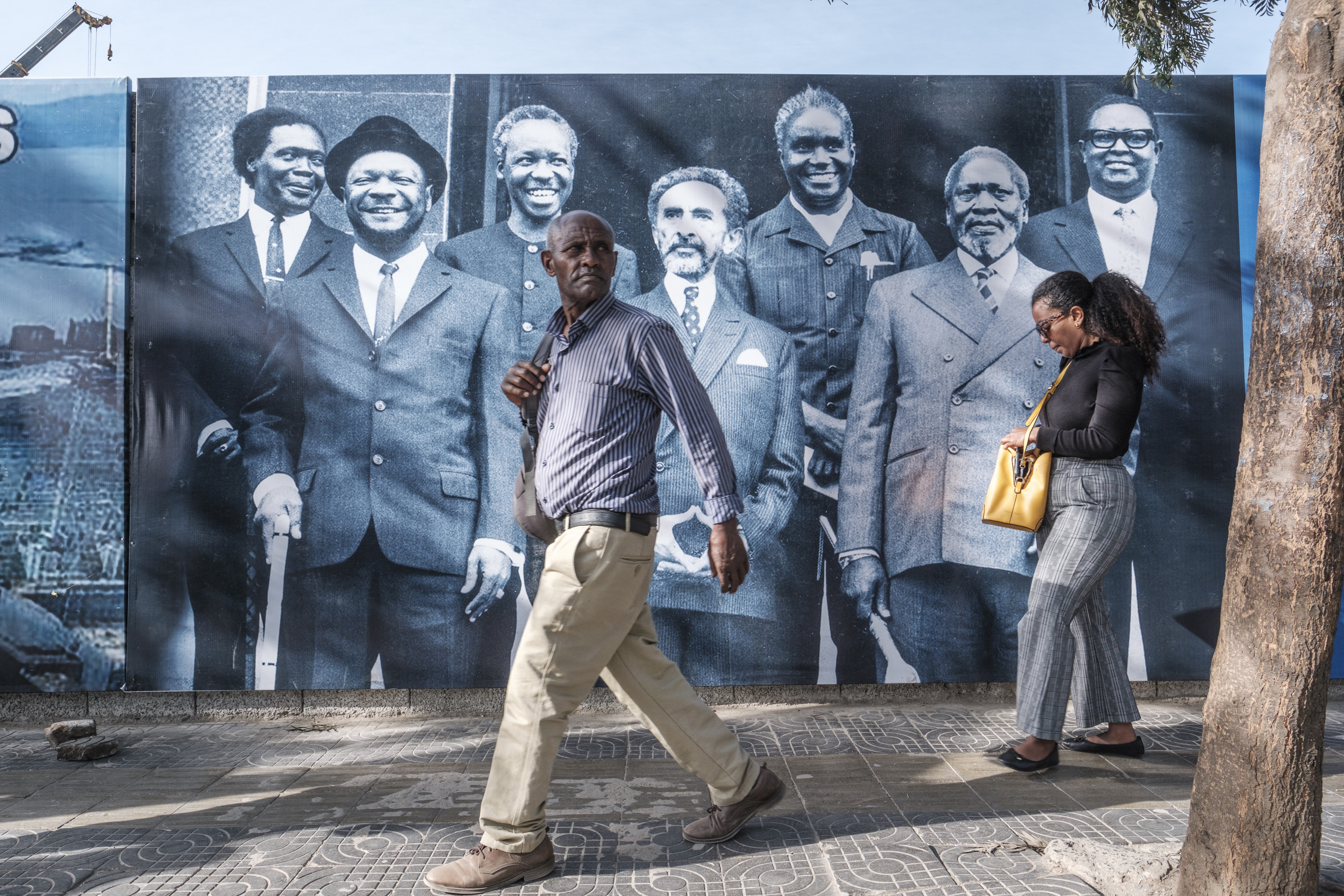 People walk in front of a banner featuring African leaders