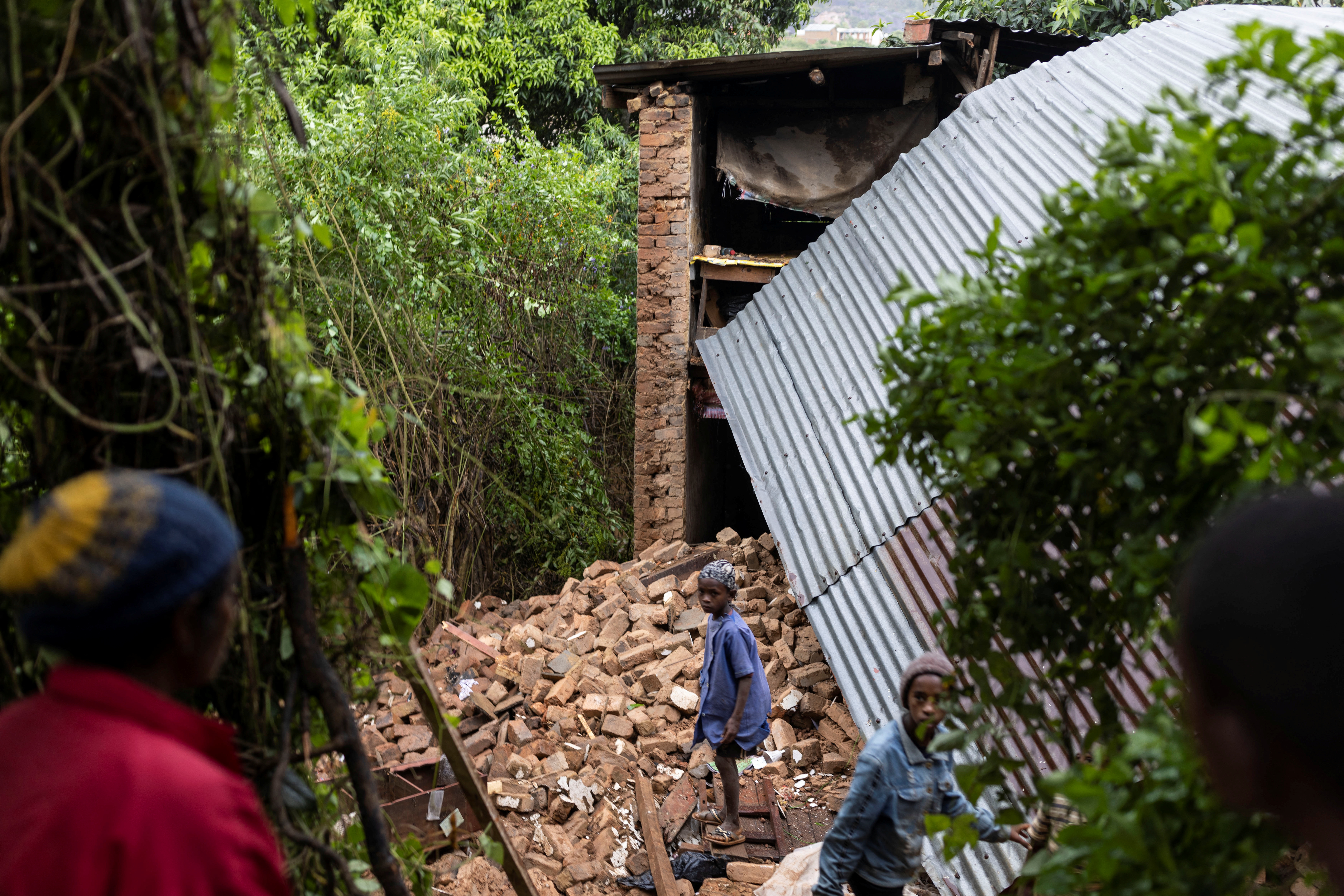 Children walk among the debris of a destroyed house