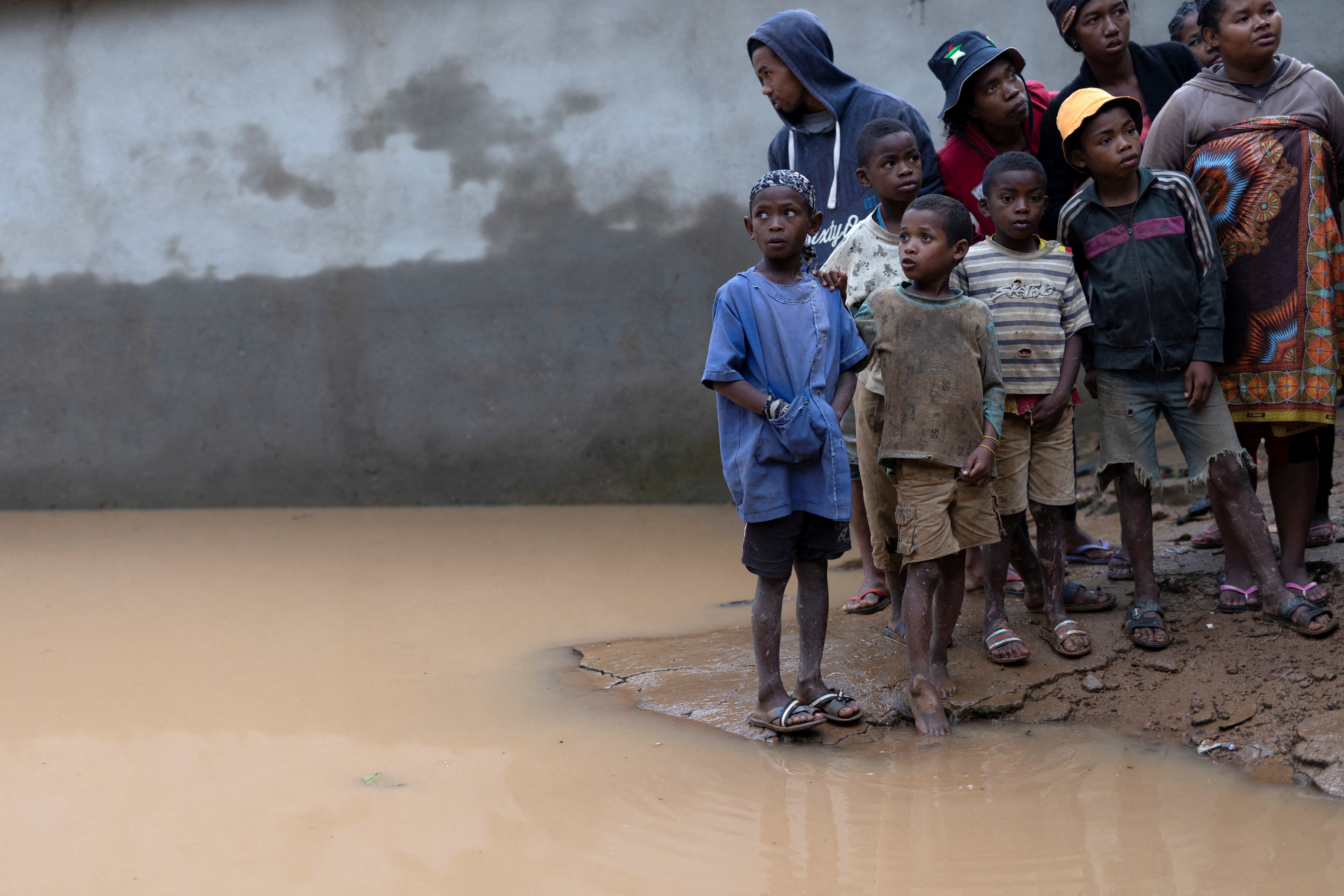 Locals stand next to a flooded area