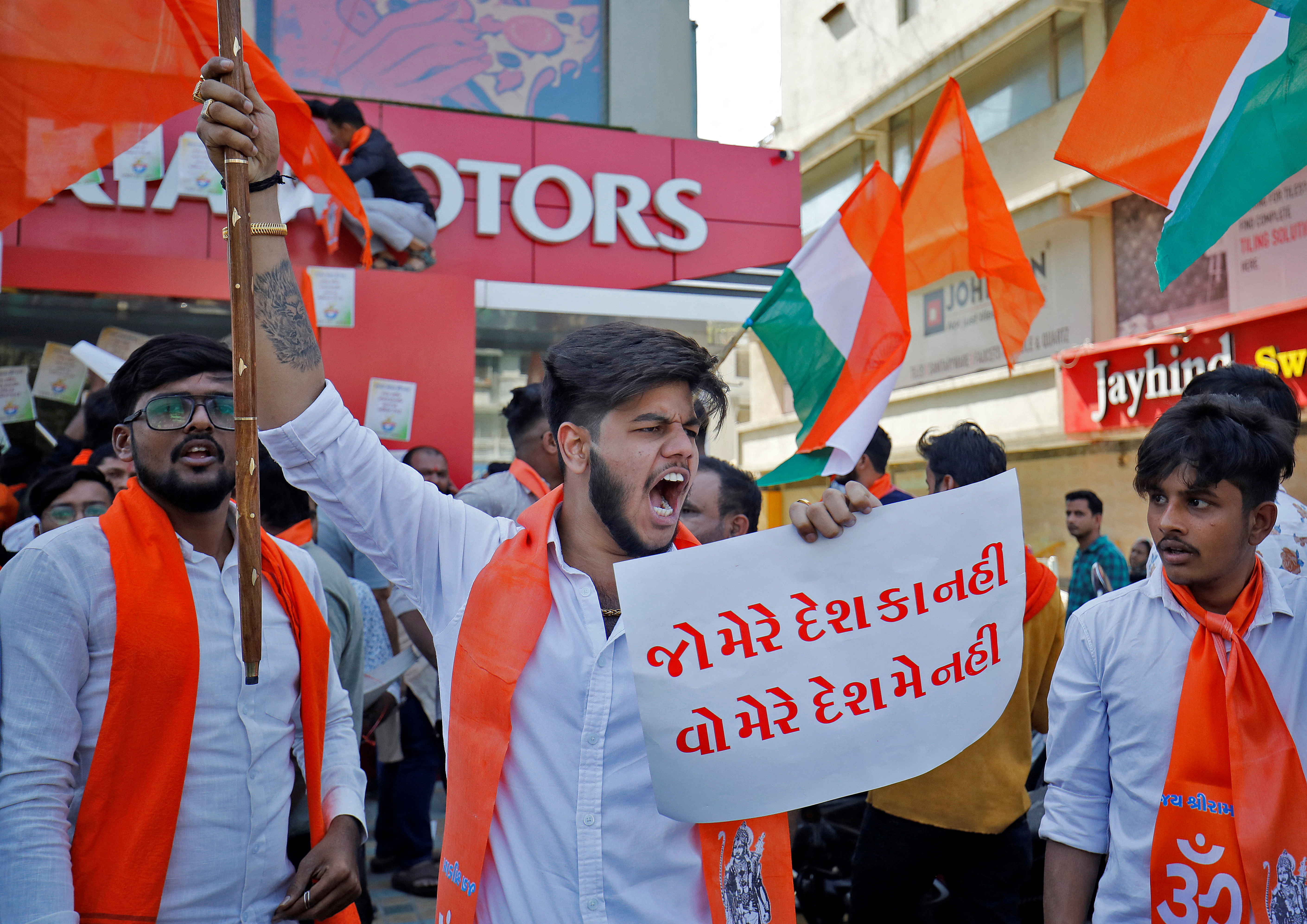 An activist of Bajrang Dal, a Hindu hardline group, shouts slogans in front of a KIA Motors showroom during a protest over their Pakistani partners' tweet in support of Kashmir, in Ahmedabad, India, February 12, 2022. The placard reads: "One who is not with my country, should not be in my country". REUTERS/Amit Dave