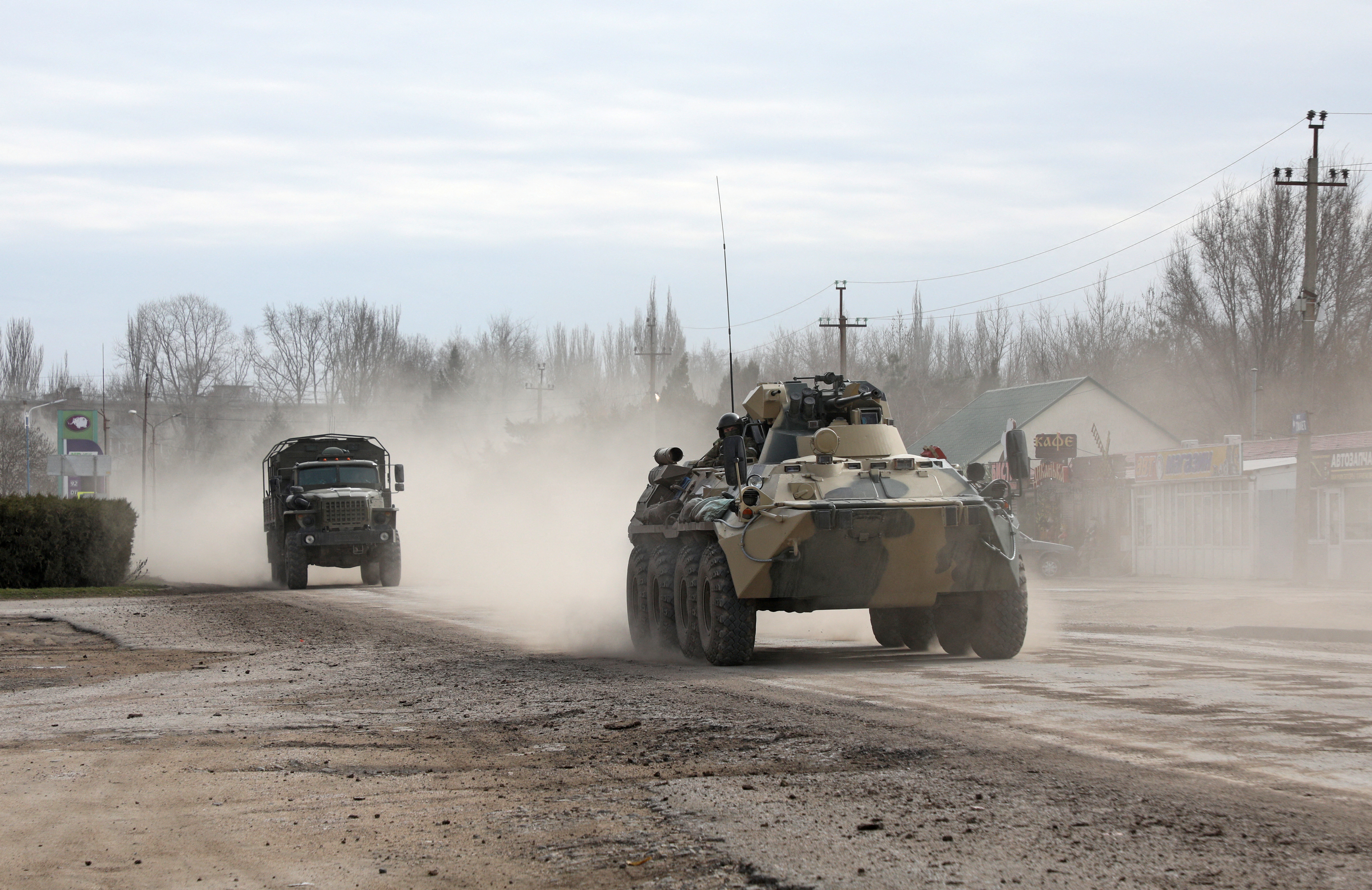 Military vehicles drive along a street