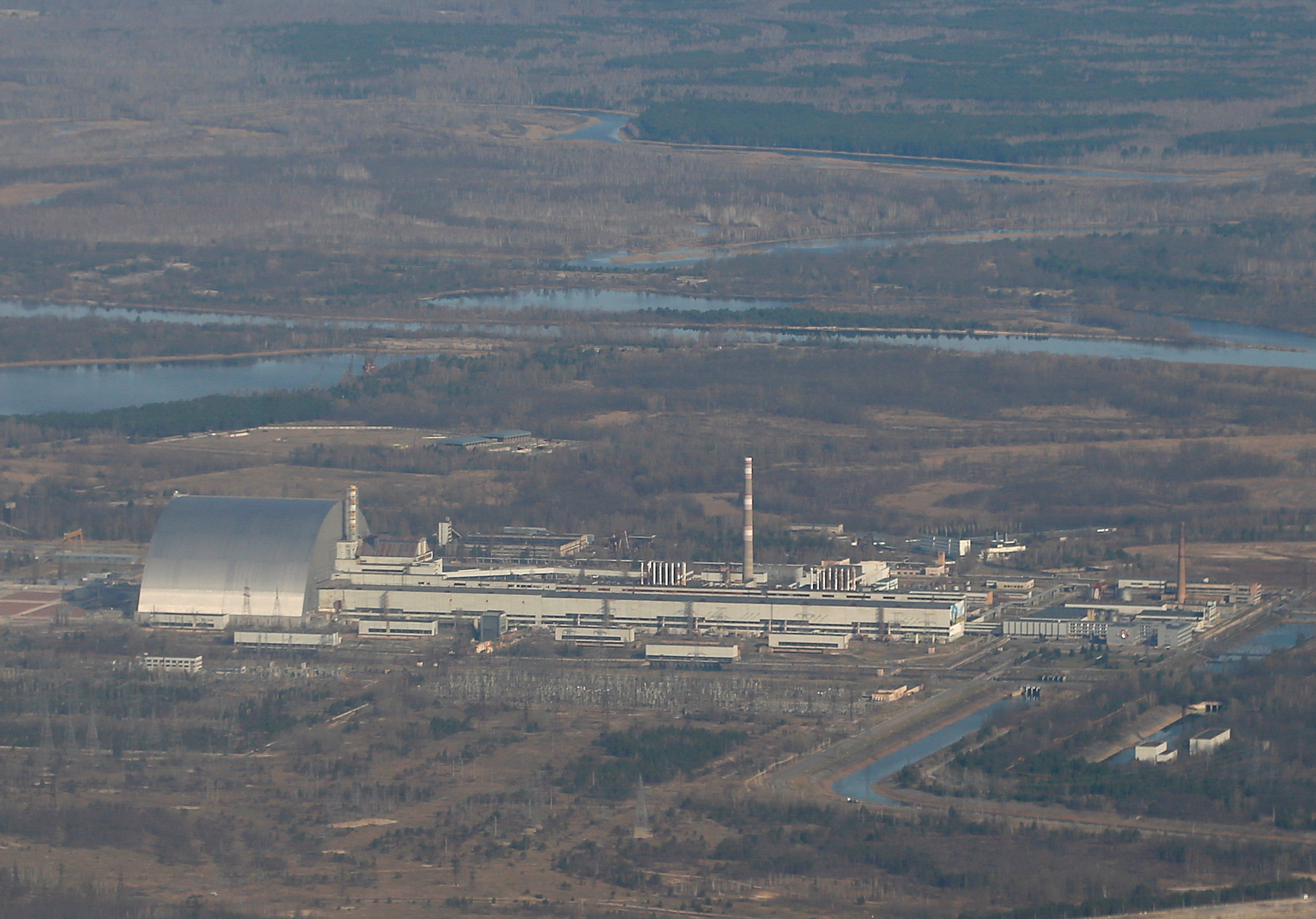 An aerial view from a plane shows a New Safe Confinement (NSC) structure over the old sarcophagus covering the damaged fourth reactor at the Chernobyl Nuclear Power Plant during a tour to the Chernobyl