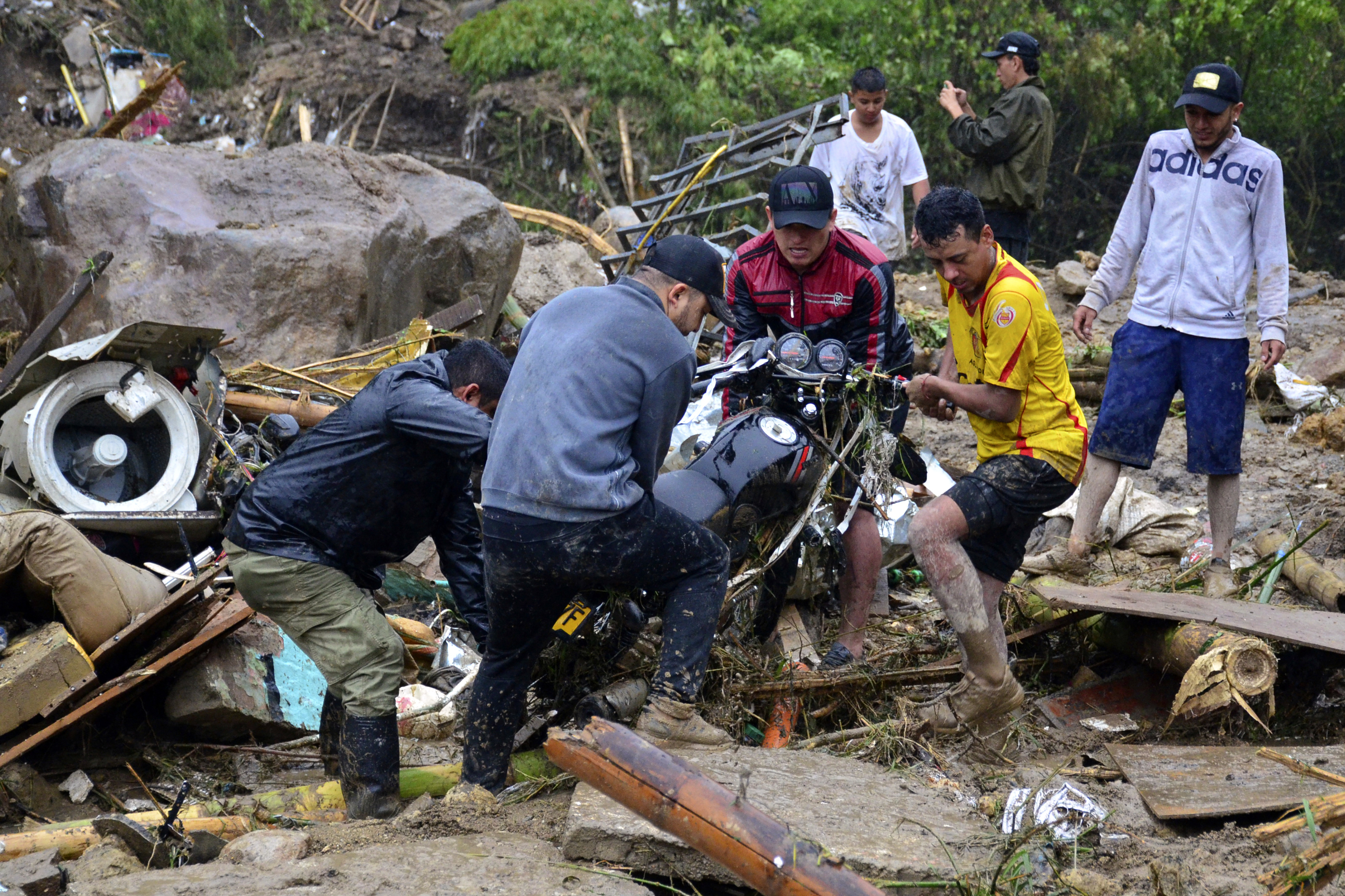 Residents lift a motorcycle from the debris