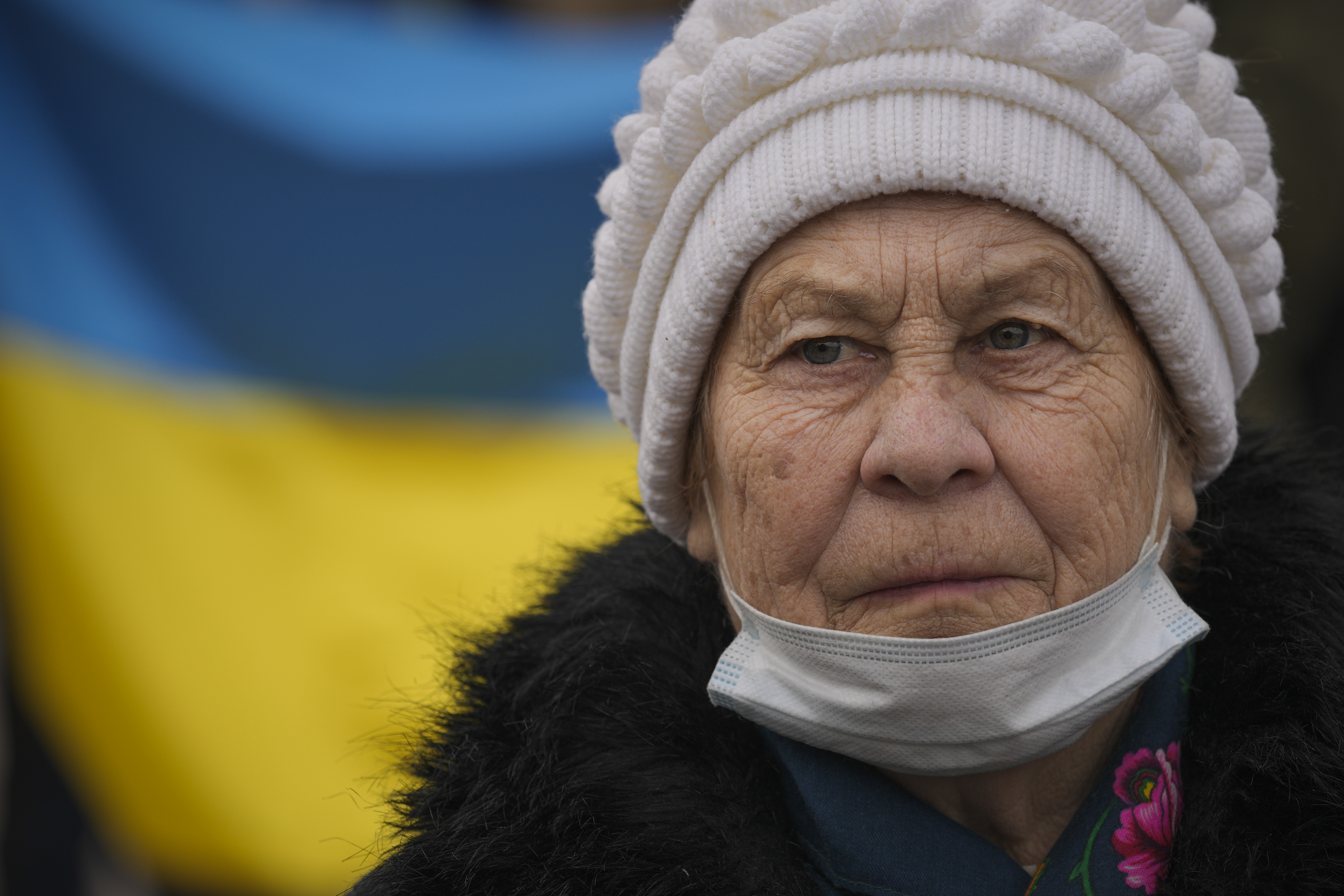 An elderly lady looks at people carrying a large Ukrainian flag as they mark a "day of unity" in Sievierodonetsk, the Luhansk region