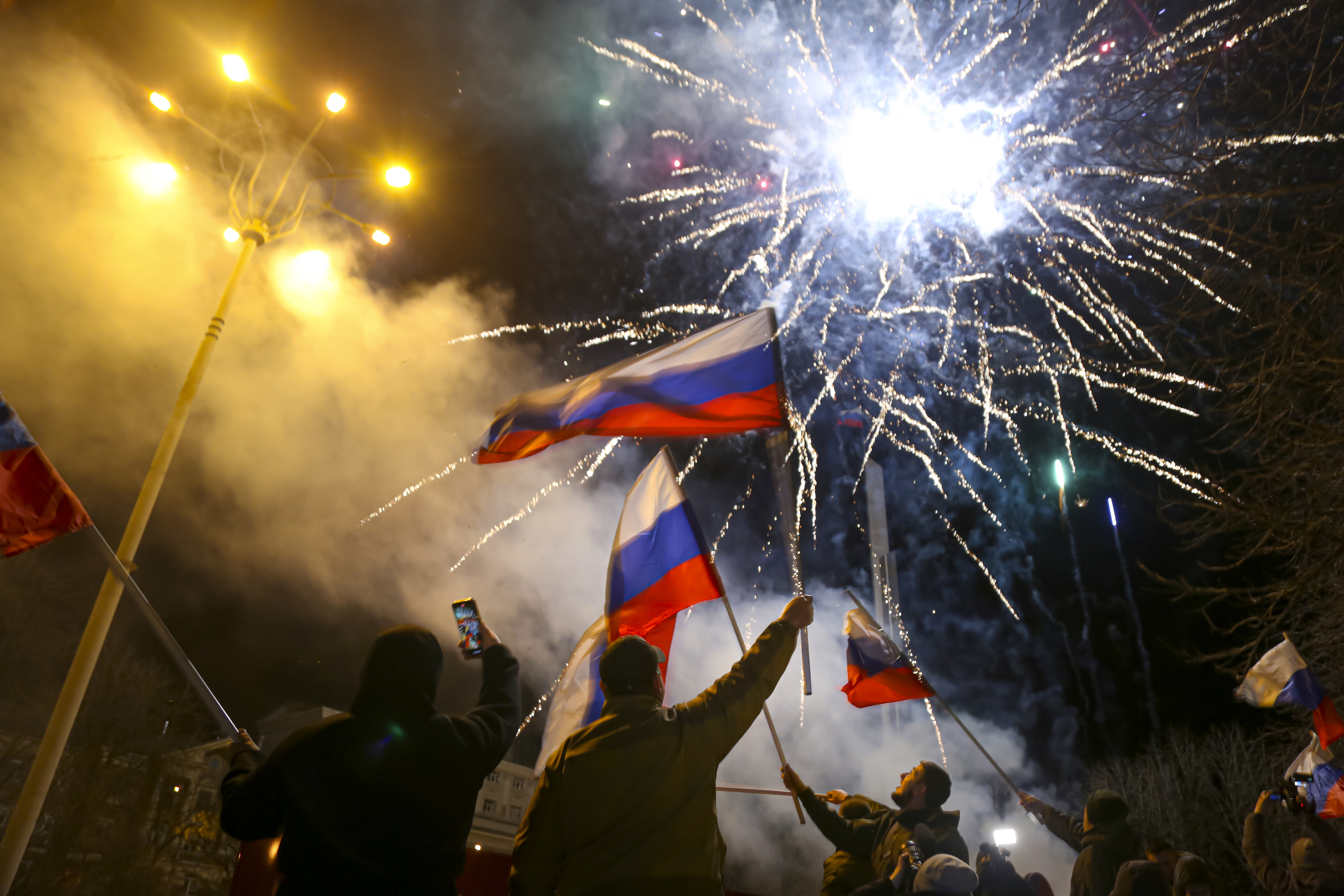 People in Donetsk wave Russian national flags celebrating Moscow's recognition of the breakaway region of Ukraine